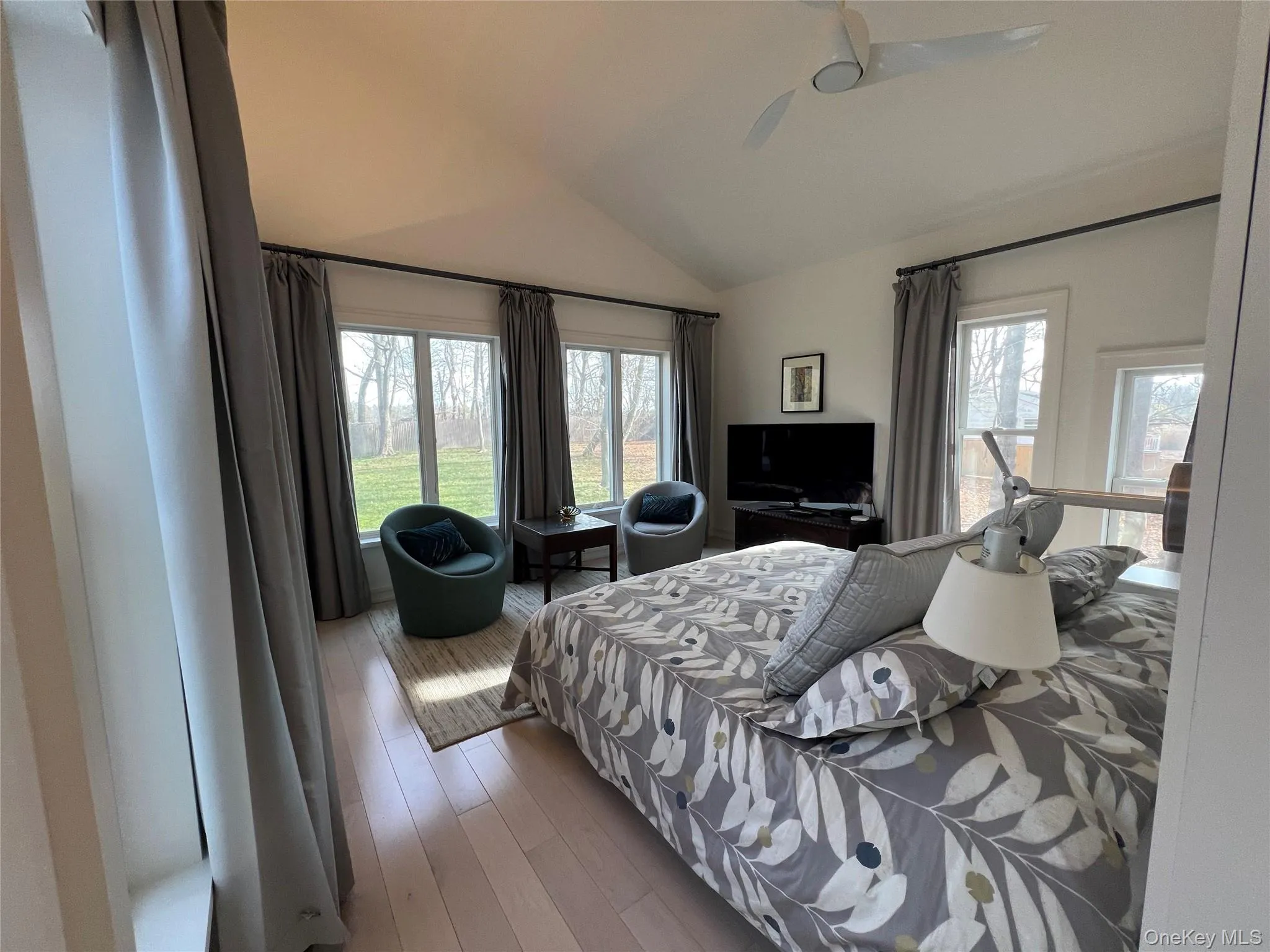 Primary Bedroom lofted ceiling, hardwood / wood-style floors, a ceiling fan, and multiple windows Primary Bedroom lofted ceiling, hardwood / wood-style floors, a ceiling fan, and multiple windows