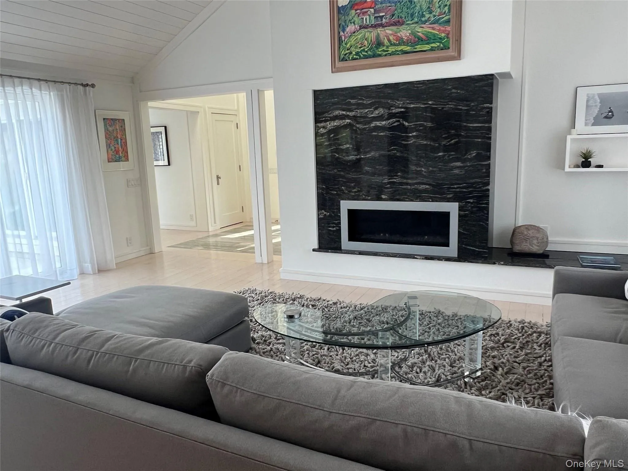 Living room with a fireplace, lofted ceiling, and light wood- flooring Living room with a fireplace, lofted ceiling, and light wood- flooring