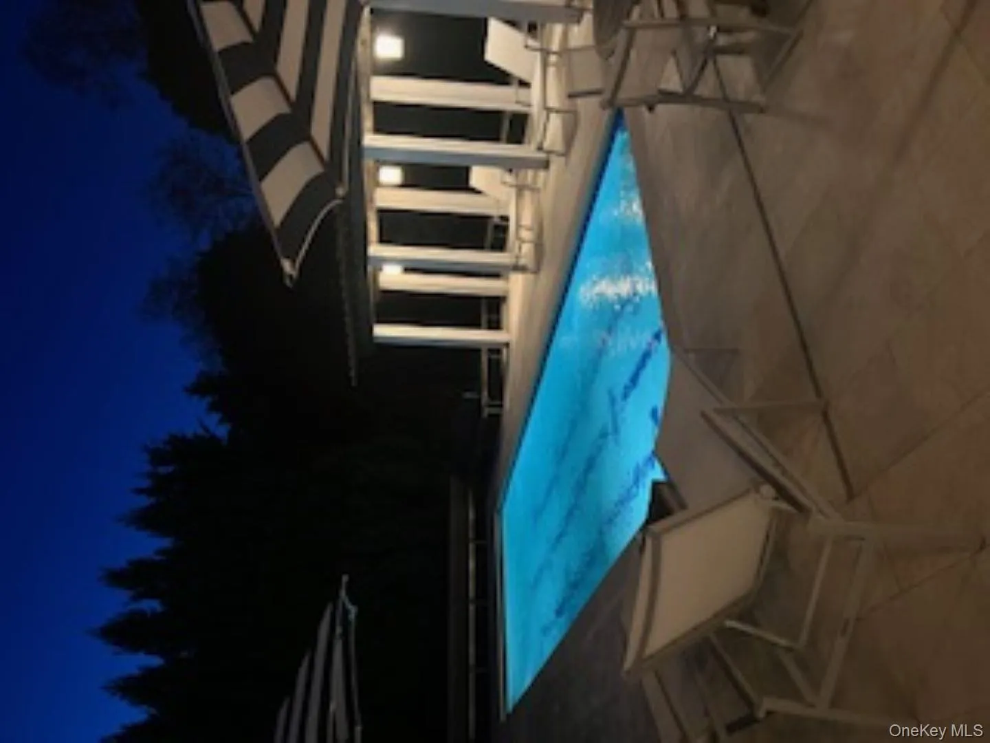 Pool at twilight with an outdoor pool and a patio area Pool at twilight with an outdoor pool and a patio area