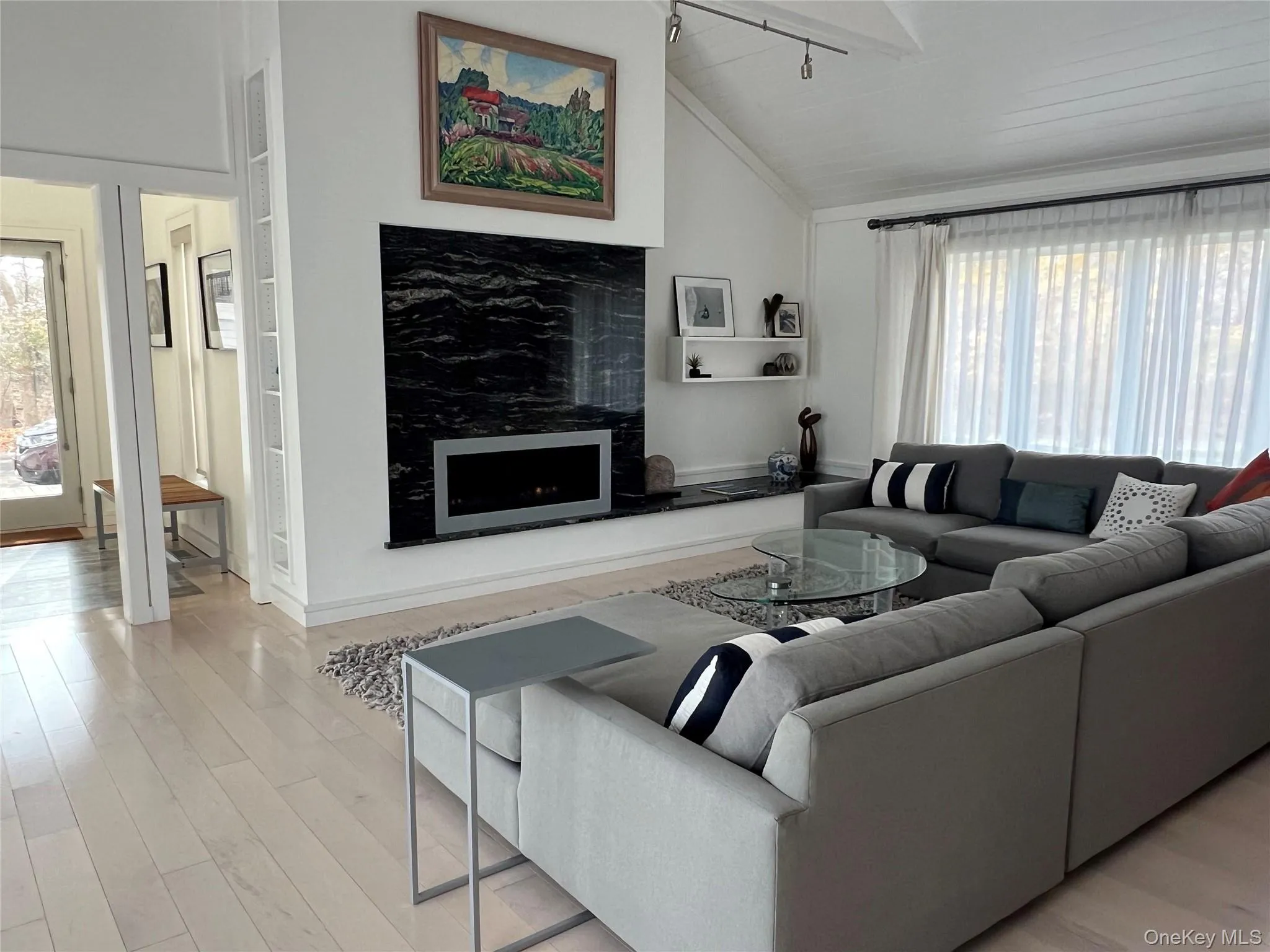 Living room featuring lofted ceiling, a fireplace, and wood finished floors Living room featuring lofted ceiling, a fireplace, and wood finished floors