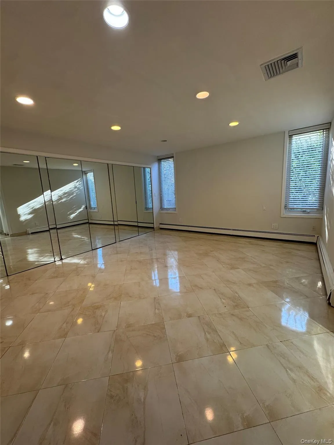 Unfurnished bedroom featuring multiple windows, recessed lighting, light marble finish flooring, and baseboard heating Unfurnished bedroom featuring multiple windows, recessed lighting, light marble finish flooring, and baseboard heating