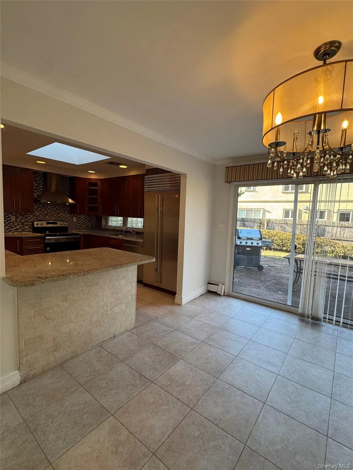 Kitchen with pendant lighting, appliances with stainless steel finishes, wall chimney exhaust hood, ornamental molding, and light stone counters Kitchen with pendant lighting, appliances with stainless steel finishes, wall chimney exhaust hood, ornamental molding, and light stone counters