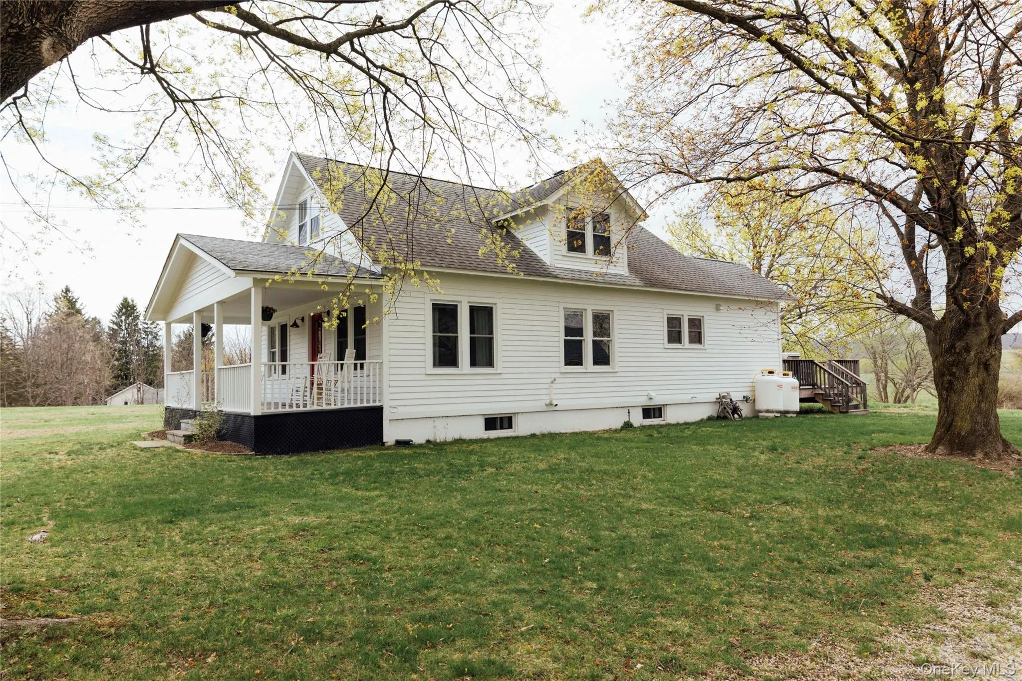 View of property exterior featuring roof with shingles, a yard, and a porch View of property exterior featuring roof with shingles, a yard, and a porch