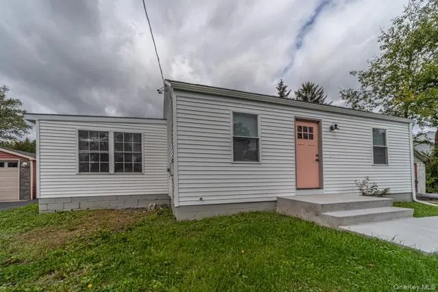 View of front of property featuring a front lawn, a detached garage, and an outdoor structure View of front of property featuring a front lawn, a detached garage, and an outdoor structure
