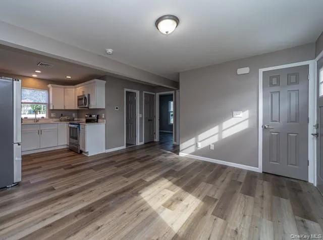 Unfurnished living room with dark wood-type flooring and baseboards Unfurnished living room with dark wood-type flooring and baseboards