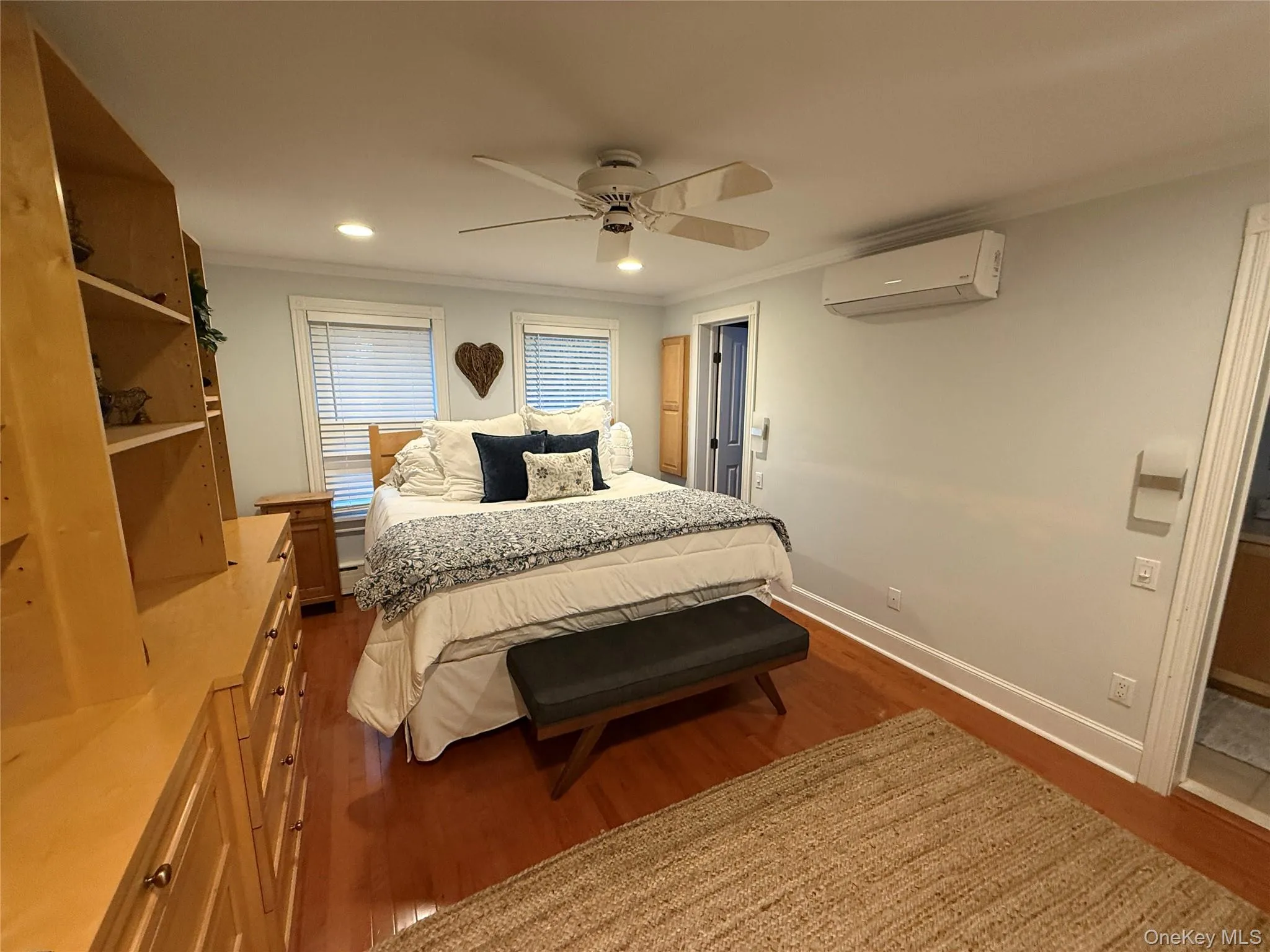 Bedroom with ornamental molding, full bath, dark wood-style floors, recessed lighting, a ceiling fan, and a wall unit AC Bedroom with ornamental molding, full bath, dark wood-style floors, recessed lighting, a ceiling fan, and a wall unit AC