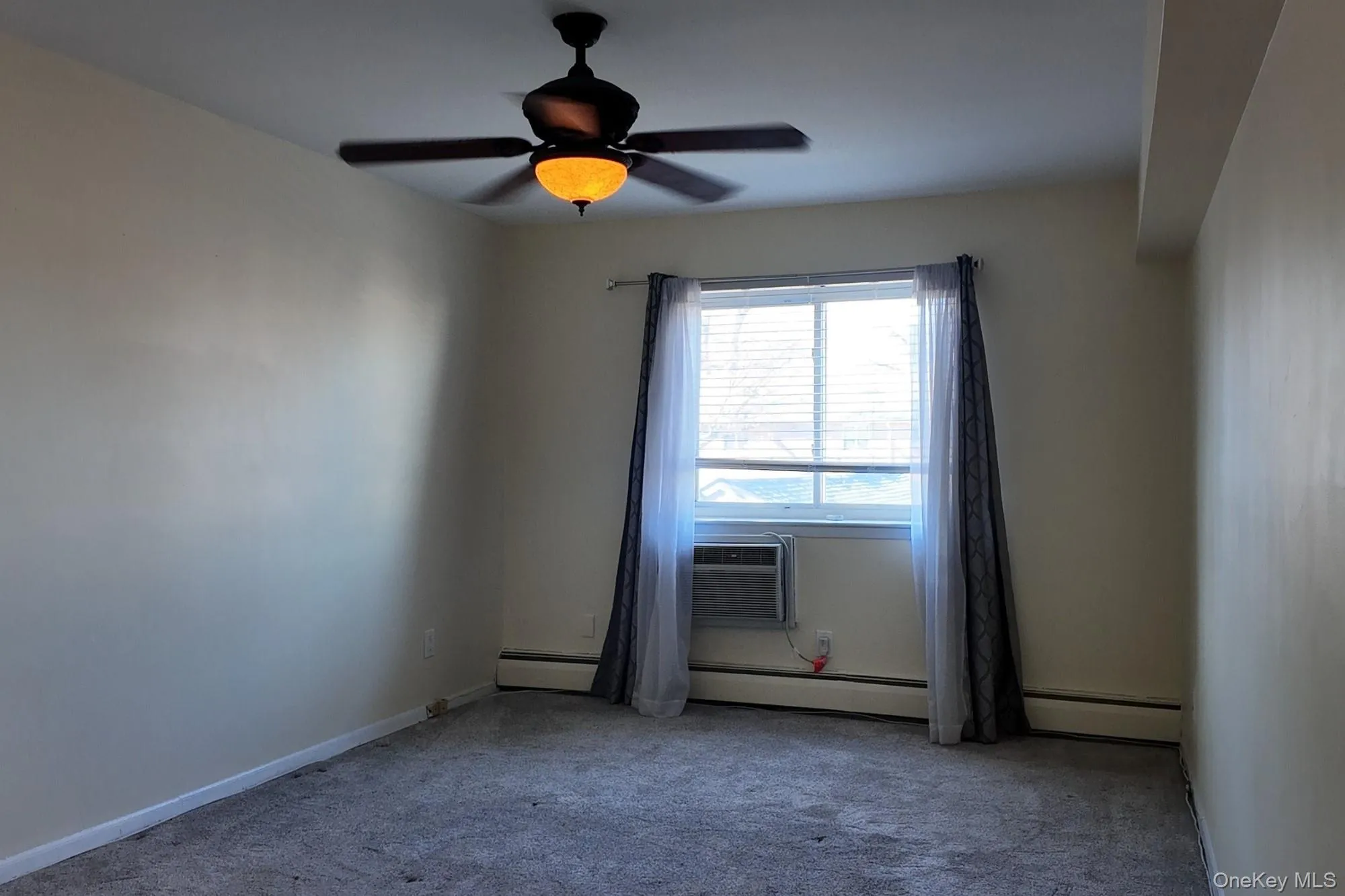 Unfurnished room featuring baseboard heating, carpet floors, and a ceiling fan Unfurnished room featuring baseboard heating, carpet floors, and a ceiling fan