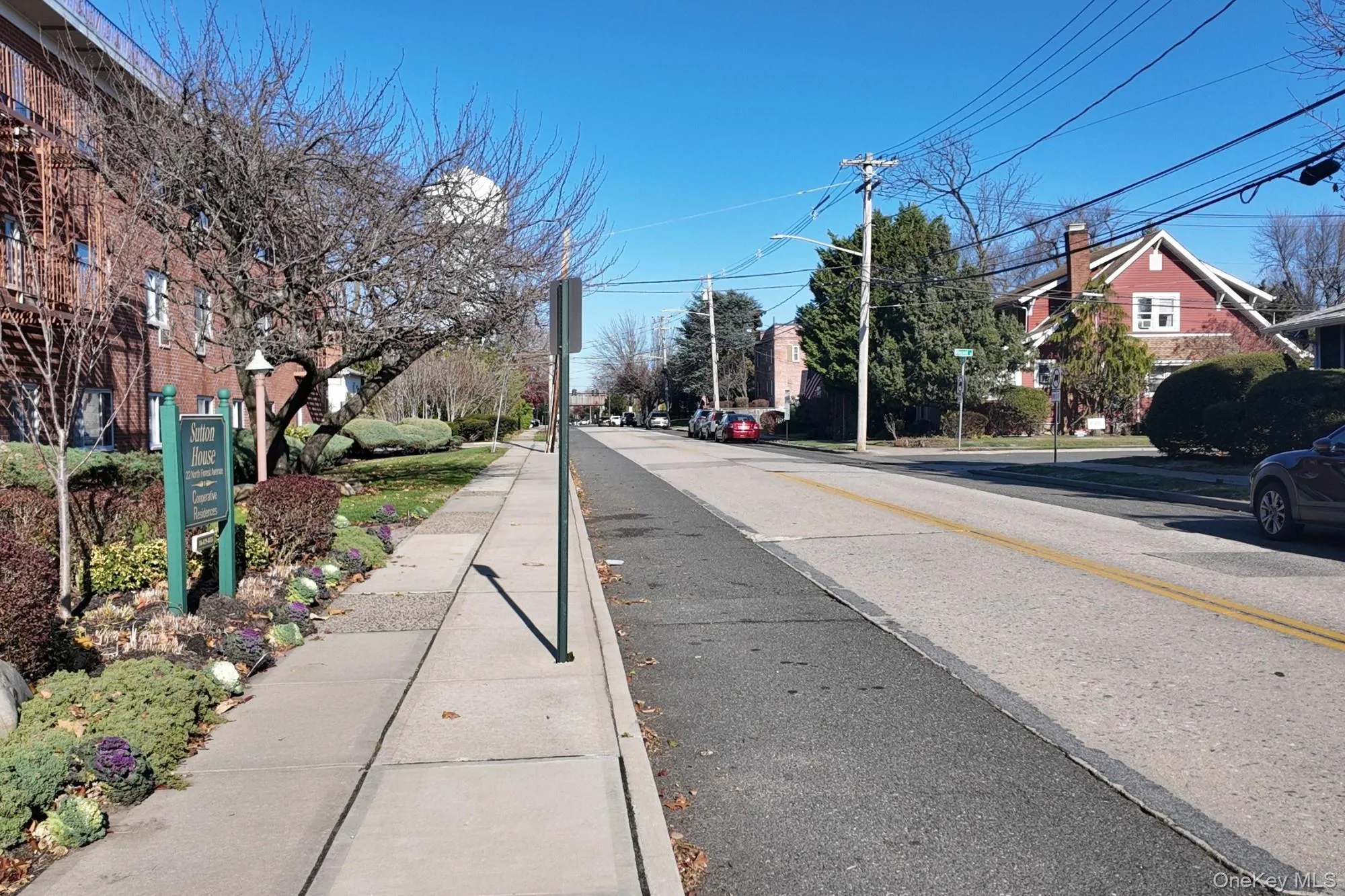 View of asphalt road featuring sidewalks, curbs, street lights, a residential view, and traffic signs View of asphalt road featuring sidewalks, curbs, street lights, a residential view, and traffic signs