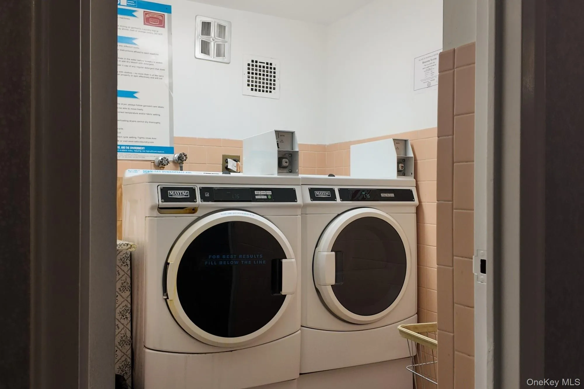 Community laundry room with washing machine and clothes dryer and tile walls Community laundry room with washing machine and clothes dryer and tile walls