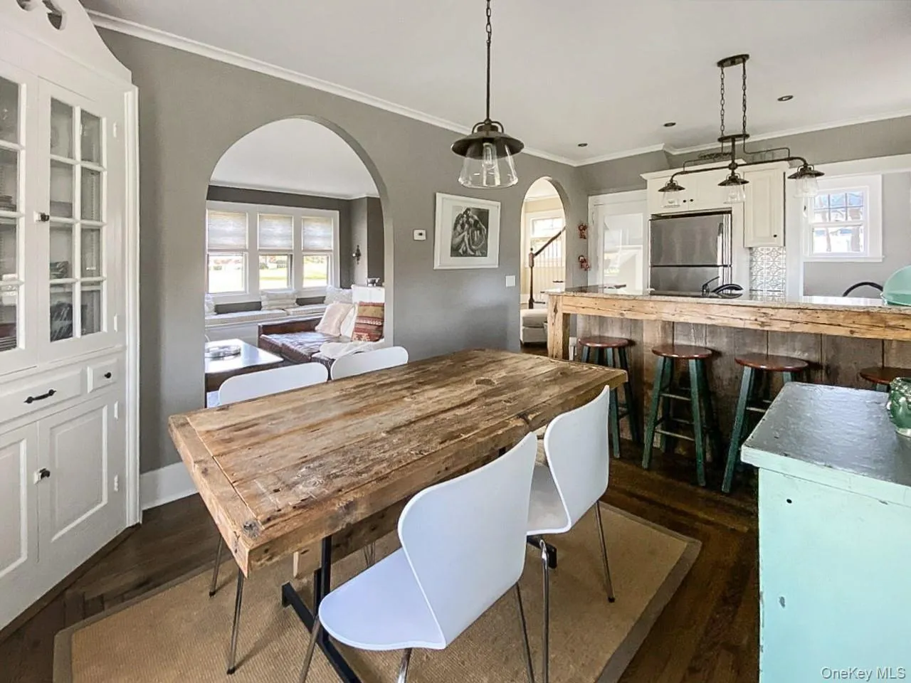 Dining area featuring ornamental molding, arched walkways, and dark wood-style floors Dining area featuring ornamental molding, arched walkways, and dark wood-style floors