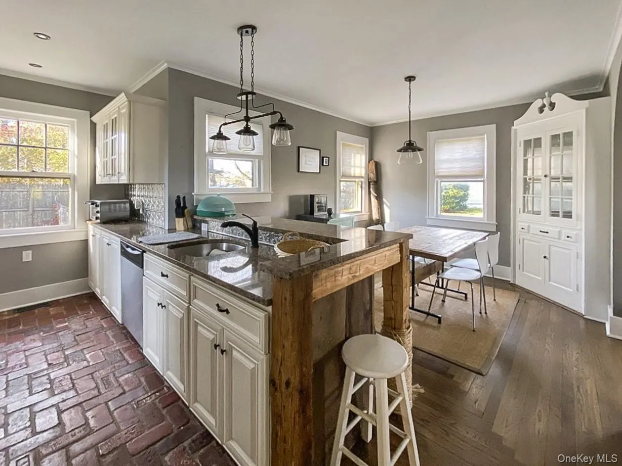 Kitchen with a kitchen bar, decorative light fixtures, a peninsula, dark stone counters, and crown molding Kitchen with a kitchen bar, decorative light fixtures, a peninsula, dark stone counters, and crown molding
