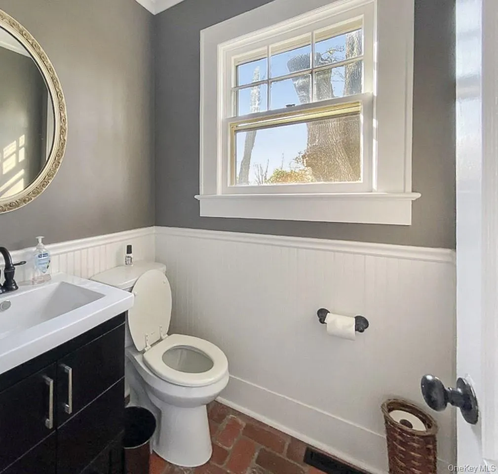 Half bathroom featuring brick flooring, wainscoting, and vanity Half bathroom featuring brick flooring, wainscoting, and vanity