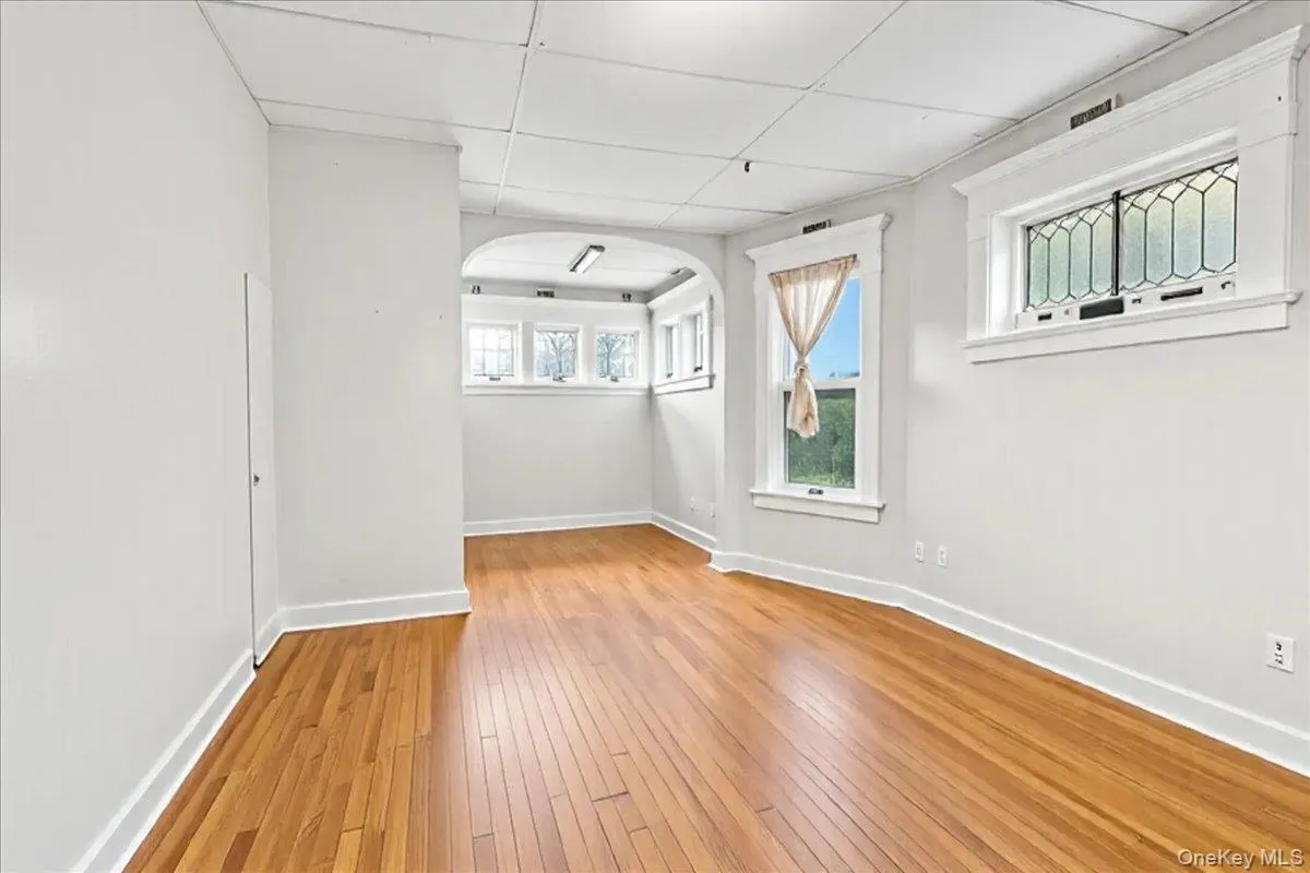 Spare room with a drop ceiling, light wood-style floors, and arched walkways Spare room with a drop ceiling, light wood-style floors, and arched walkways