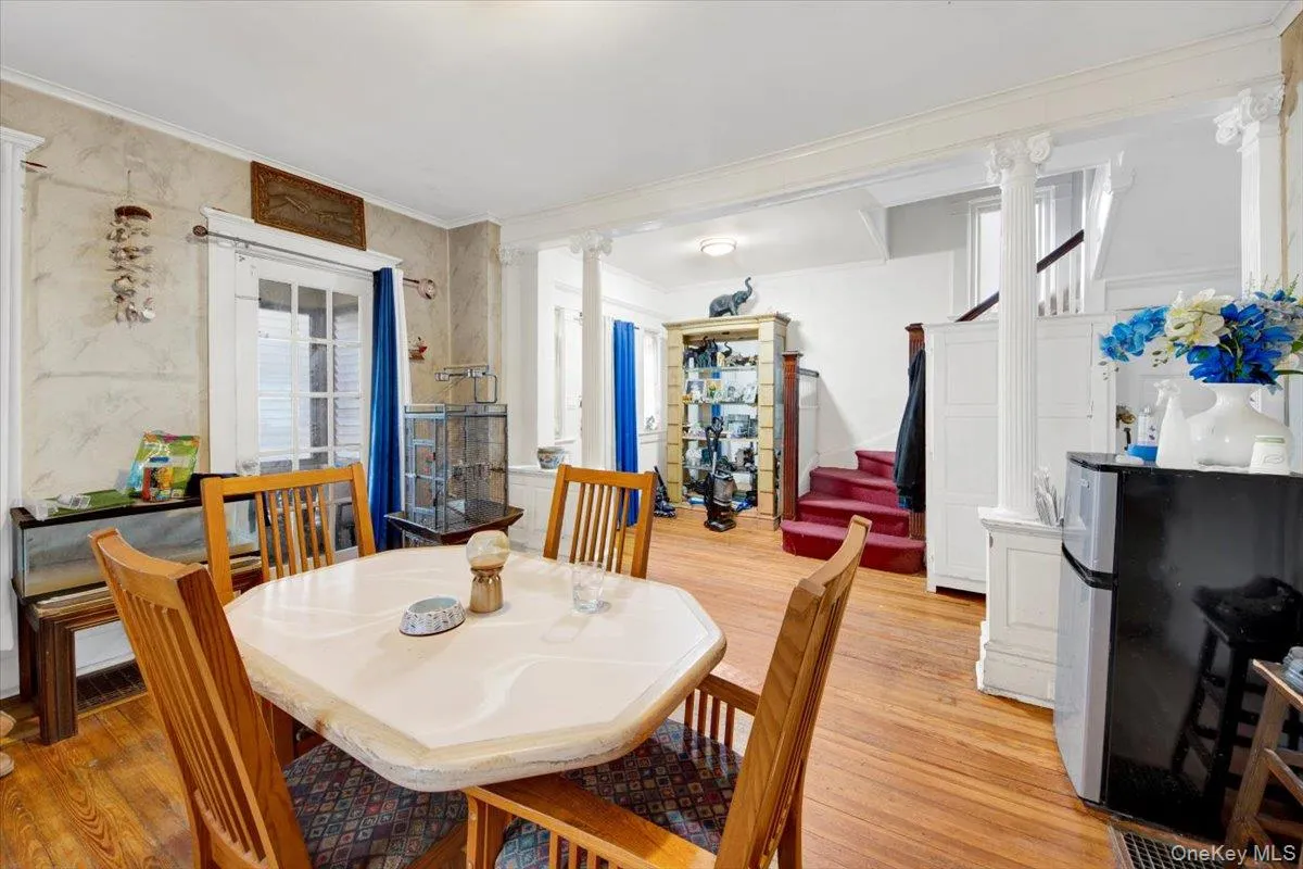 Dining area featuring decorative columns, light wood-style floors, stairway, and ornamental molding. With view into the entry foyer. Dining area featuring decorative columns, light wood-style floors, stairway, and ornamental molding. With view into the entry foyer.