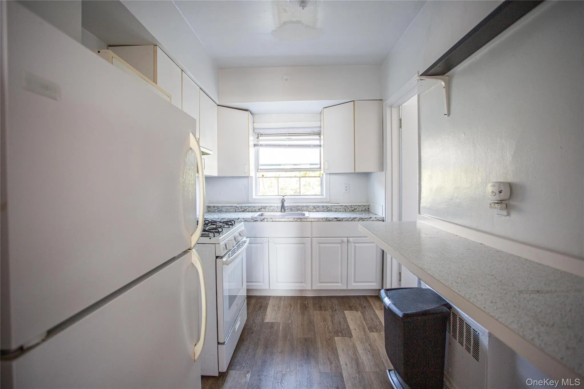 Kitchen featuring white appliances, light countertops, white cabinets, and dark wood-style flooring Kitchen featuring white appliances, light countertops, white cabinets, and dark wood-style flooring