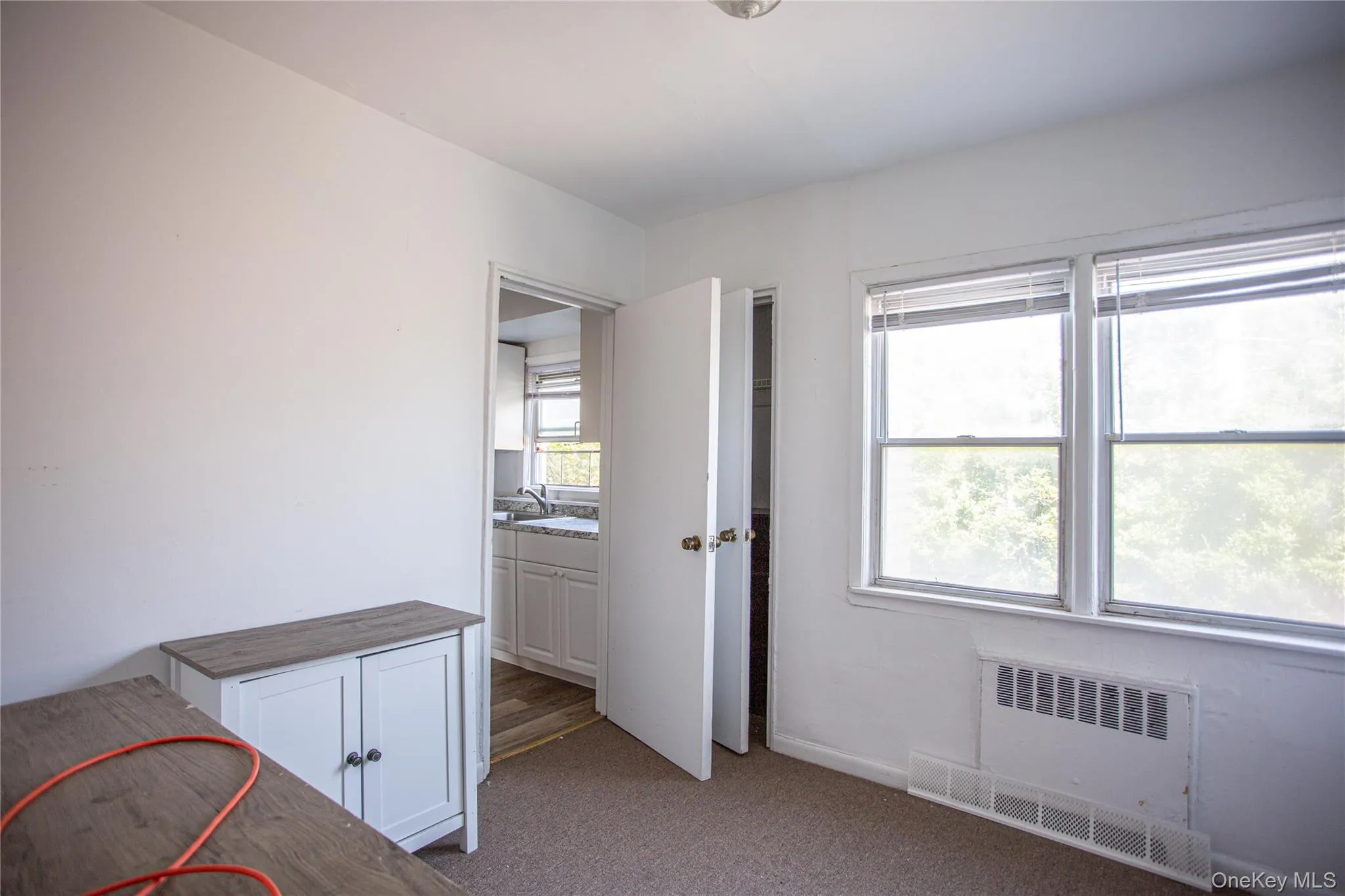 Unfurnished bedroom featuring dark carpet and radiator heating unit Unfurnished bedroom featuring dark carpet and radiator heating unit