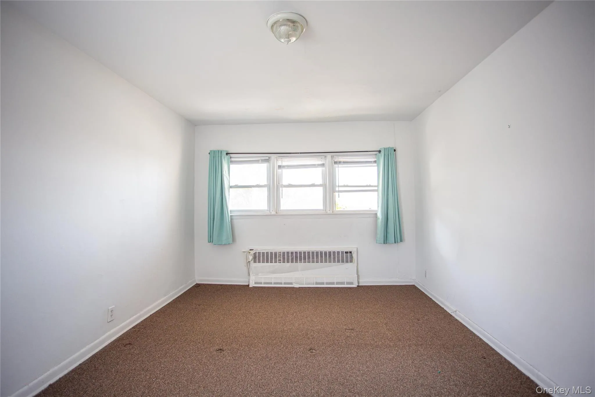 Carpeted empty room with radiator and baseboards Carpeted empty room with radiator and baseboards