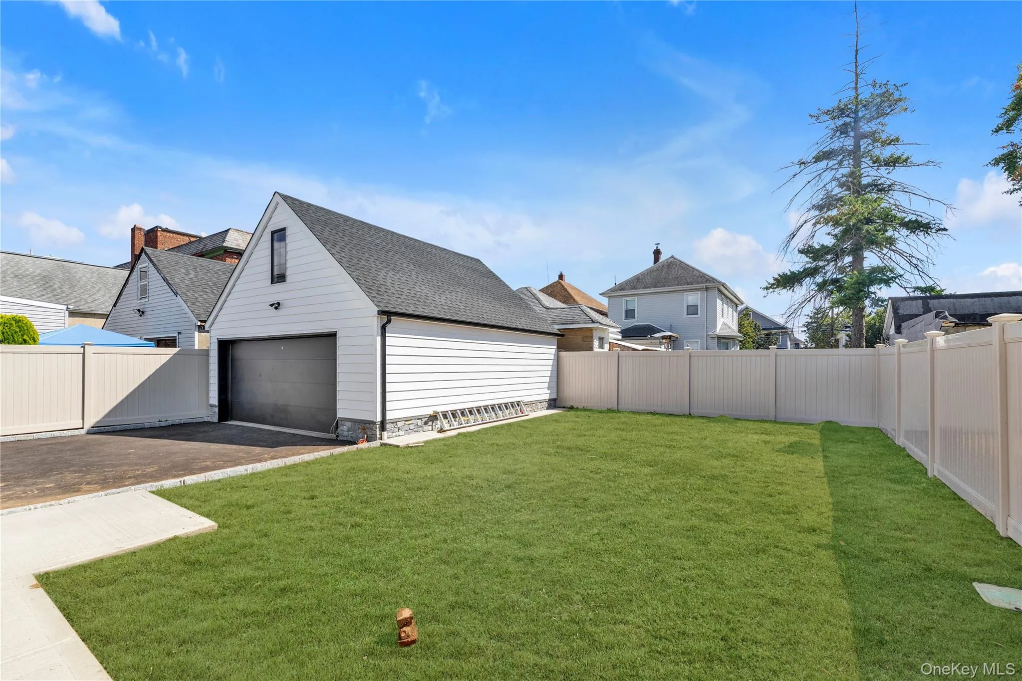 Fenced backyard featuring a garage and driveway Fenced backyard featuring a garage and driveway