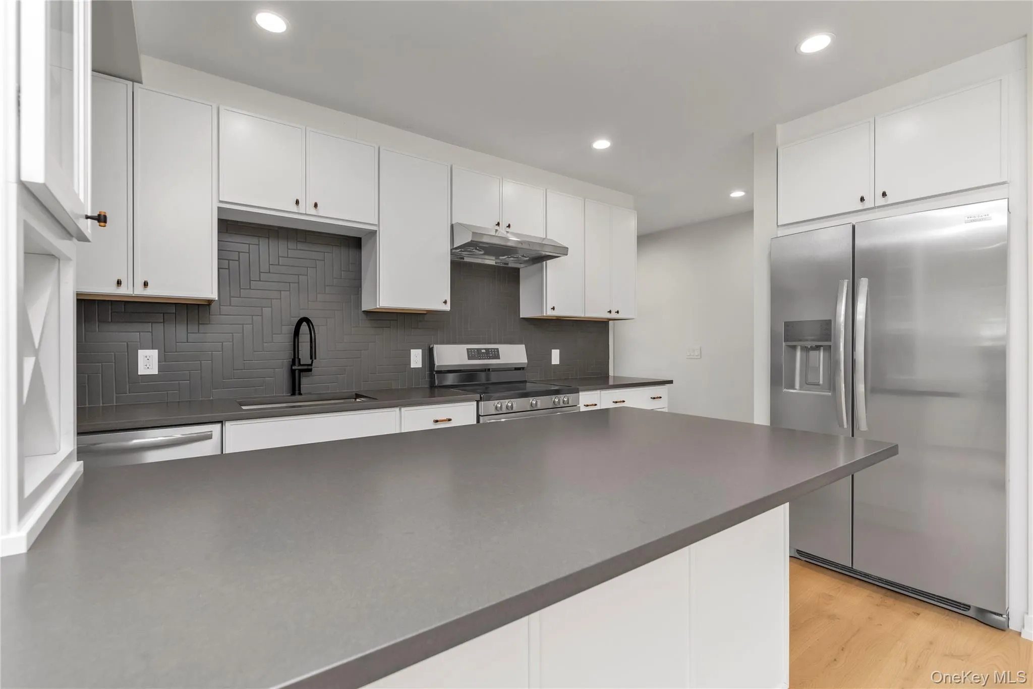 Kitchen with stainless steel appliances, decorative backsplash, dark countertops, white cabinets, and recessed lighting Kitchen with stainless steel appliances, decorative backsplash, dark countertops, white cabinets, and recessed lighting