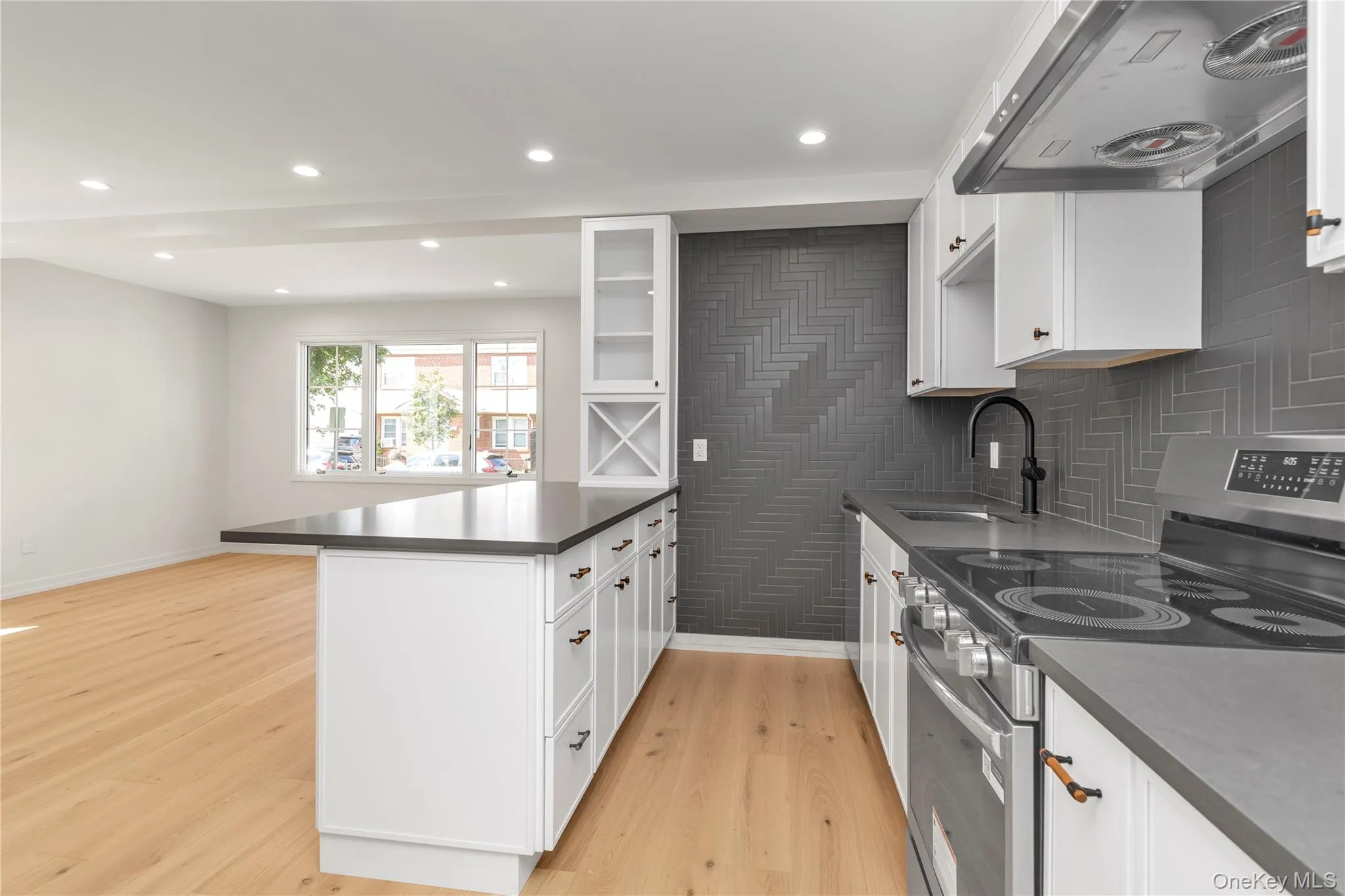 Kitchen with stainless steel electric stove, glass insert cabinets, range hood, a peninsula, and white cabinetry Kitchen with stainless steel electric stove, glass insert cabinets, range hood, a peninsula, and white cabinetry