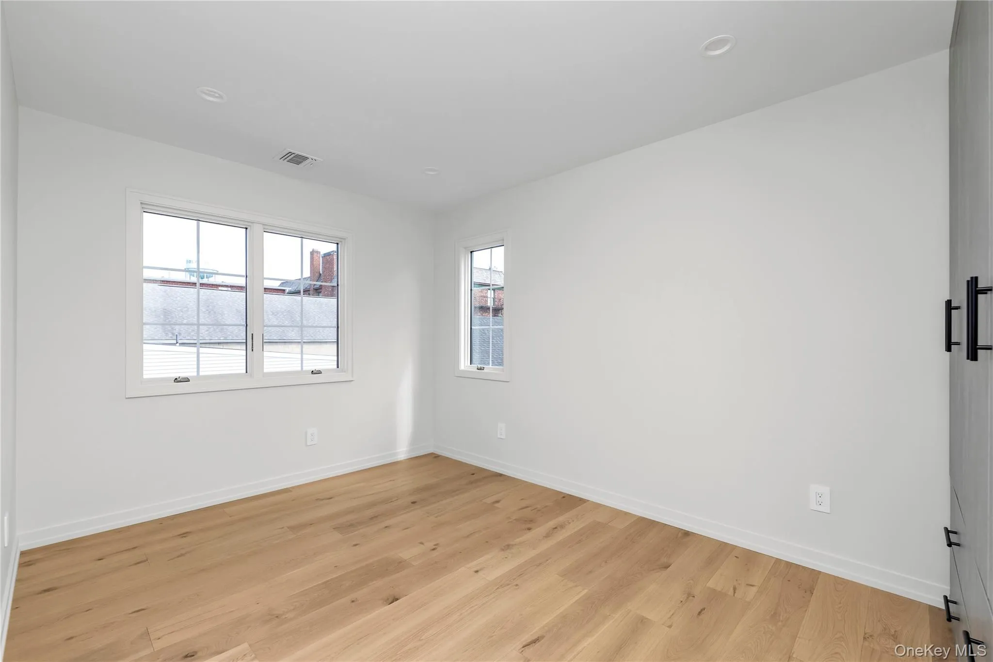 Spare room with light wood-style flooring, healthy amount of natural light, and a barn door Spare room with light wood-style flooring, healthy amount of natural light, and a barn door