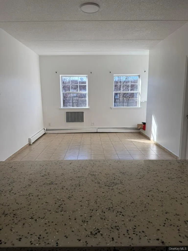 Unfurnished room with light tile patterned floors, a textured ceiling, and a baseboard heating unit Unfurnished room with light tile patterned floors, a textured ceiling, and a baseboard heating unit