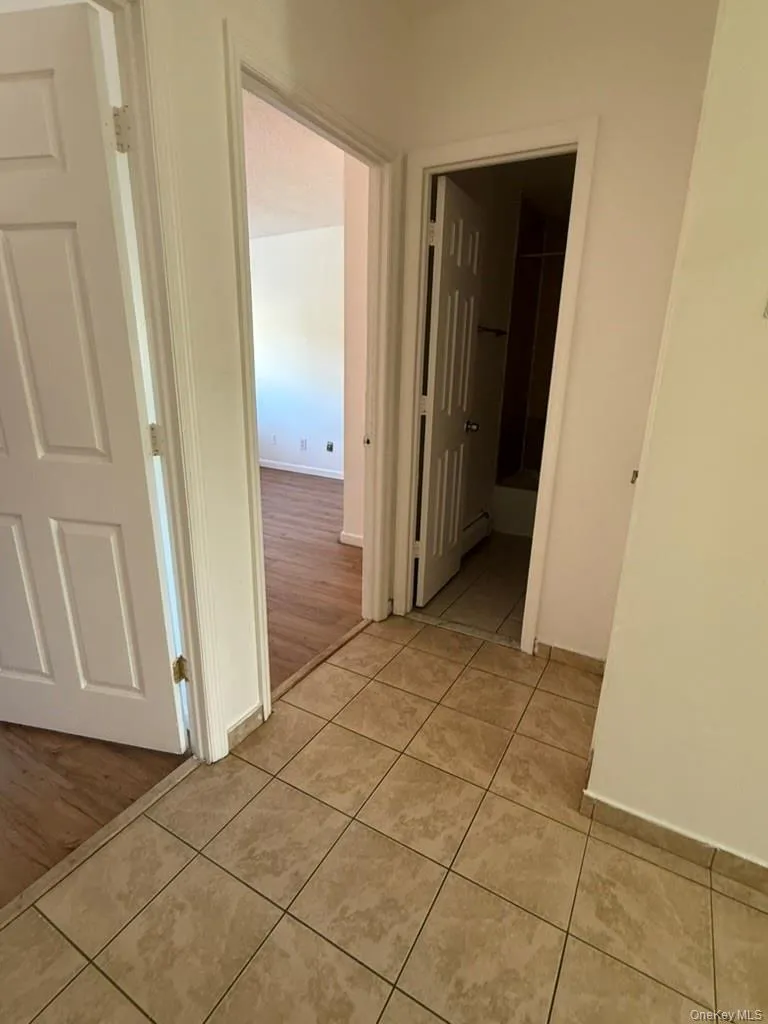 Hall with light tile patterned floors and baseboards Hall with light tile patterned floors and baseboards