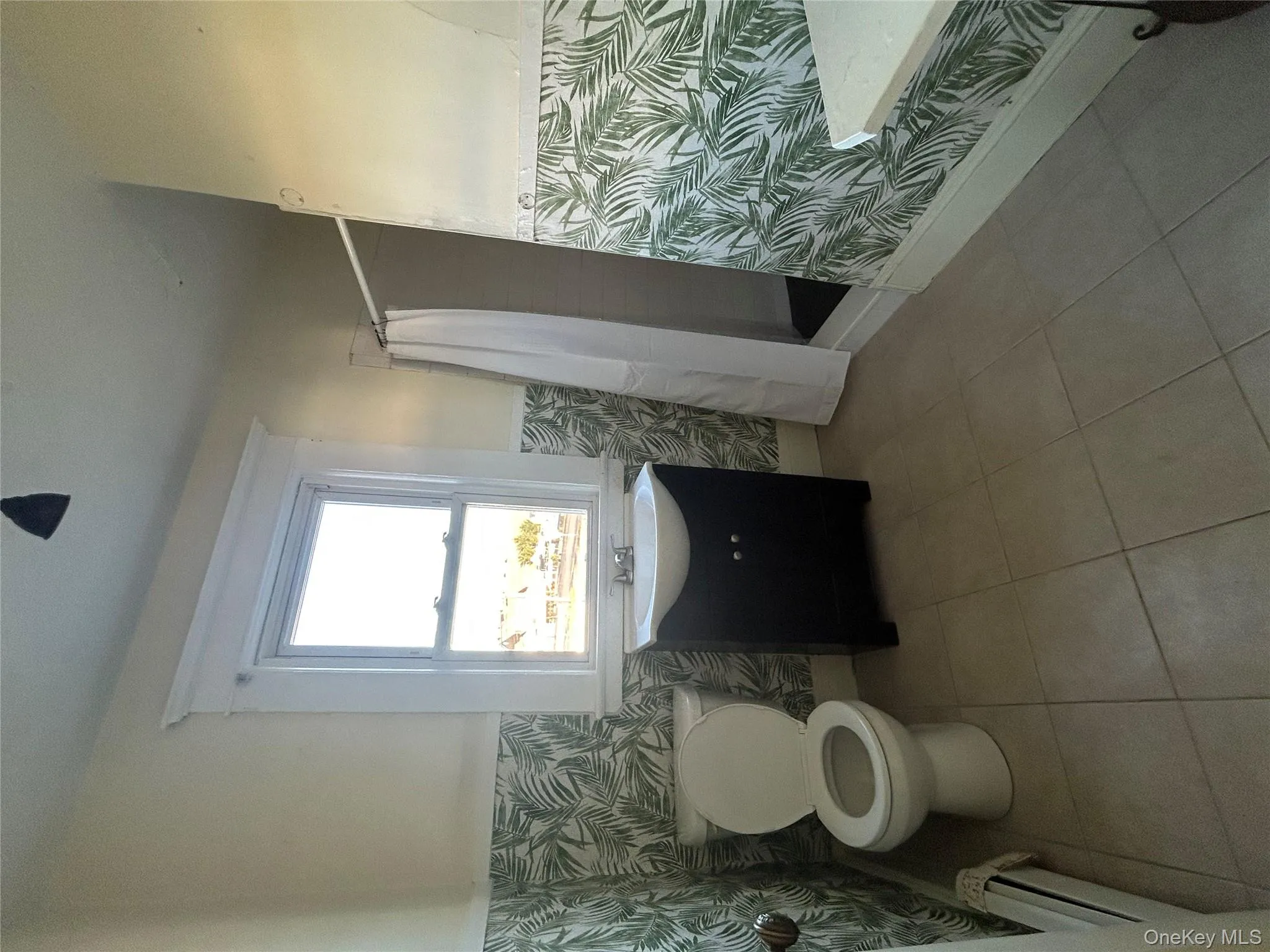 Full bath featuring vanity, wallpapered walls, a stall shower, a wainscoted wall, and baseboard heating Full bath featuring vanity, wallpapered walls, a stall shower, a wainscoted wall, and baseboard heating