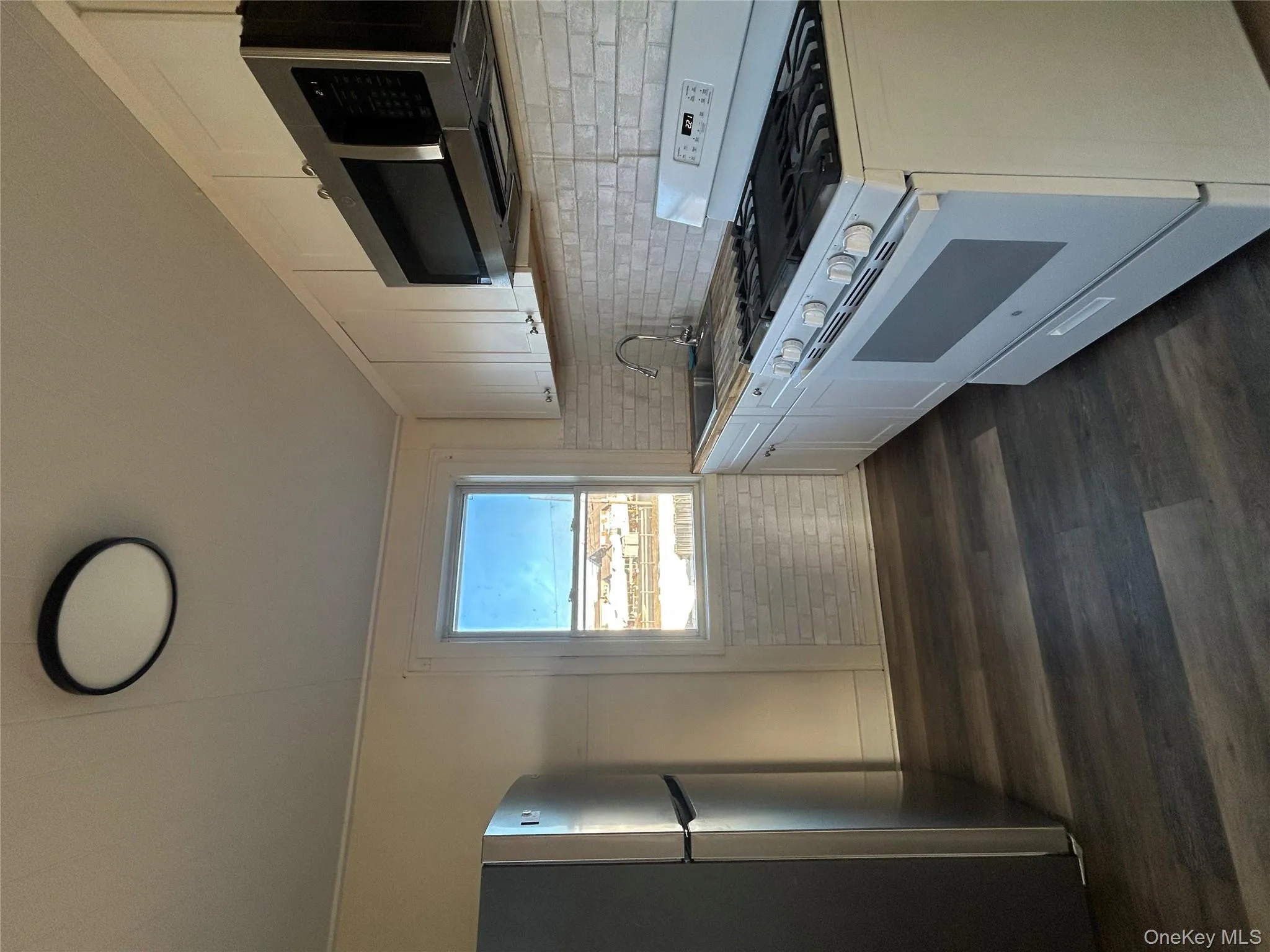 Kitchen with stainless steel range, fridge, white microwave, and white cabinets Kitchen with stainless steel range, fridge, white microwave, and white cabinets