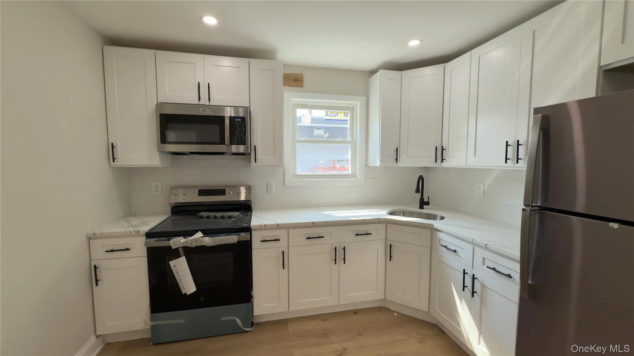 Kitchen featuring appliances with stainless steel finishes, white cabinets, decorative backsplash, light wood-style flooring, and recessed lighting Kitchen featuring appliances with stainless steel finishes, white cabinets, decorative backsplash, light wood-style flooring, and recessed lighting