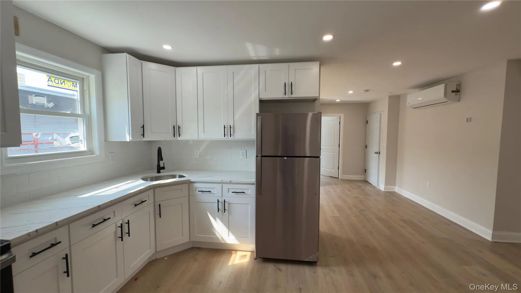 Kitchen with freestanding refrigerator, white cabinetry, light stone countertops, light wood-type flooring, and recessed lighting Kitchen with freestanding refrigerator, white cabinetry, light stone countertops, light wood-type flooring, and recessed lighting