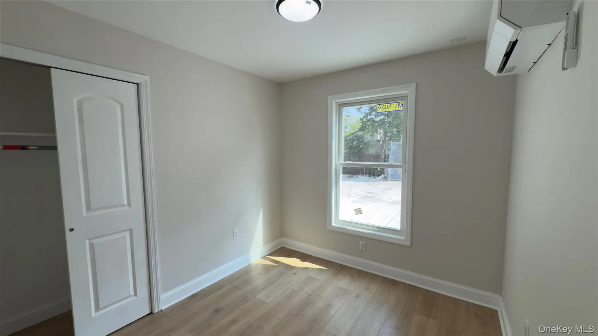 Unfurnished bedroom with a closet, light wood-style flooring, and an AC wall unit Unfurnished bedroom with a closet, light wood-style flooring, and an AC wall unit