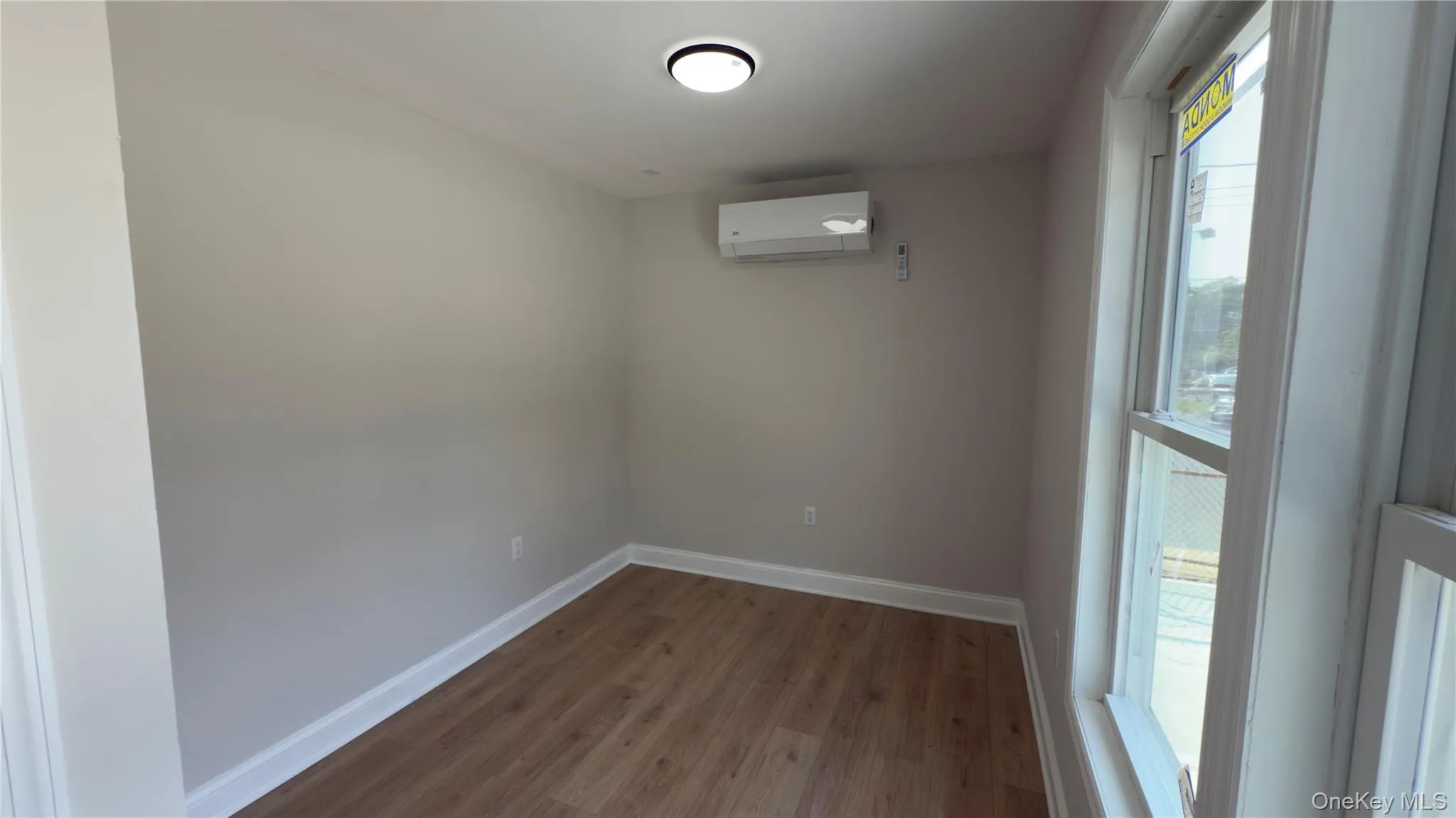 Unfurnished room featuring wood finished floors and a wall mounted air conditioner Unfurnished room featuring wood finished floors and a wall mounted air conditioner