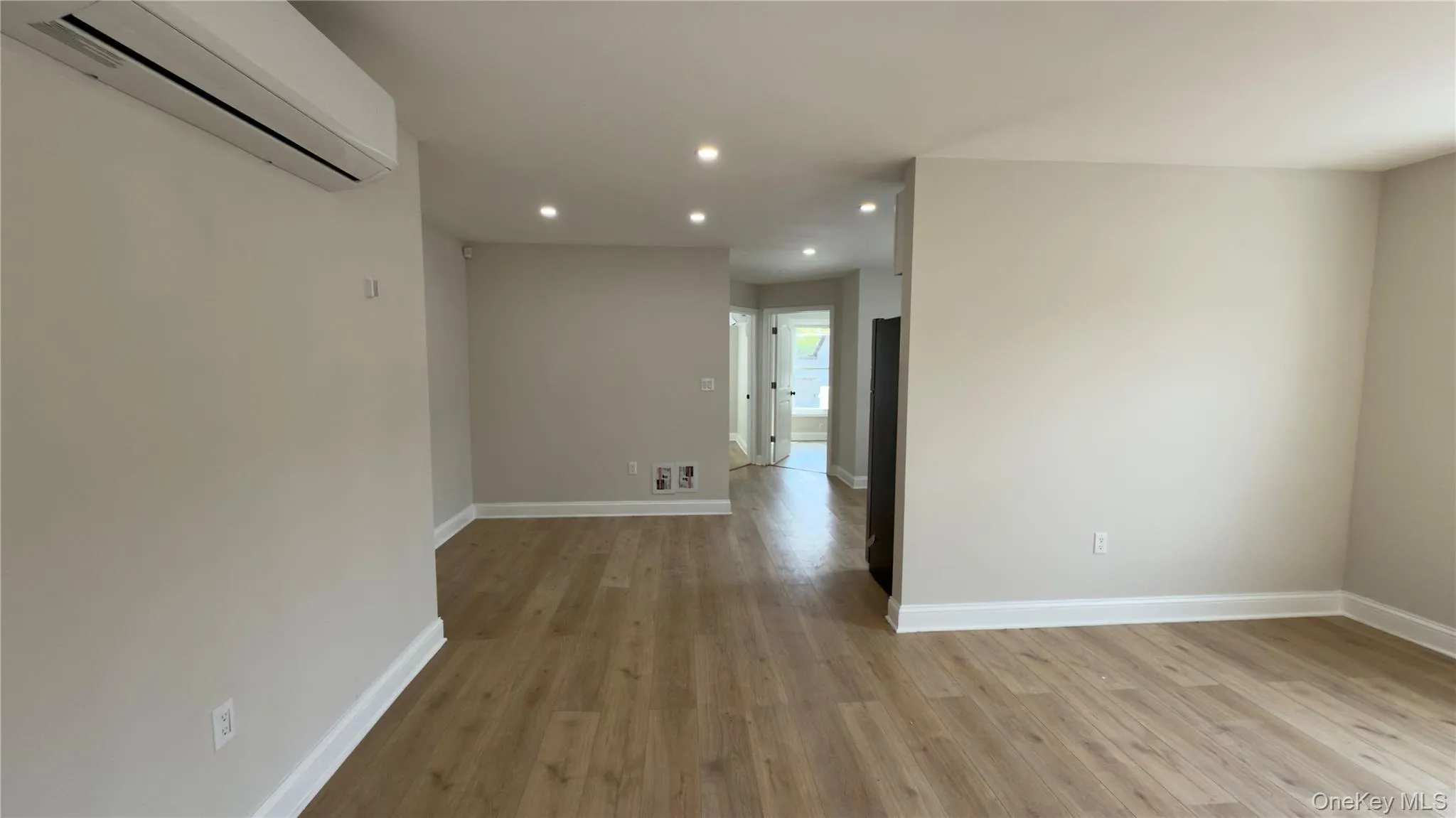 Empty room featuring recessed lighting, a wall mounted air conditioner, and light wood finished floors Empty room featuring recessed lighting, a wall mounted air conditioner, and light wood finished floors