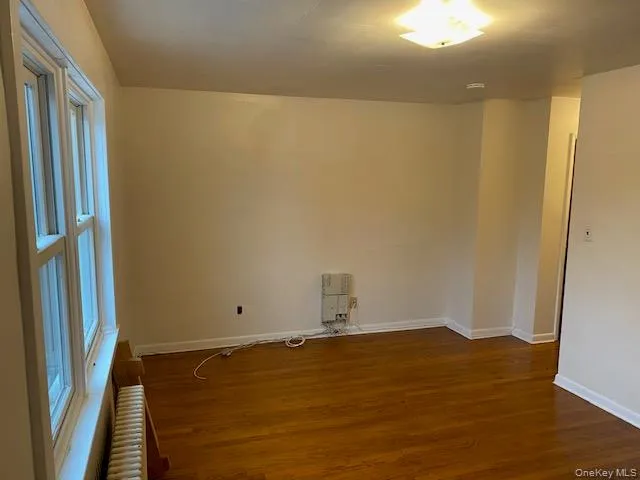 Unfurnished room with radiator heating unit and dark wood-type flooring Unfurnished room with radiator heating unit and dark wood-type flooring