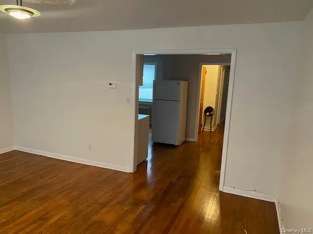 Spare room featuring dark wood-style flooring and radiator heating unit Spare room featuring dark wood-style flooring and radiator heating unit