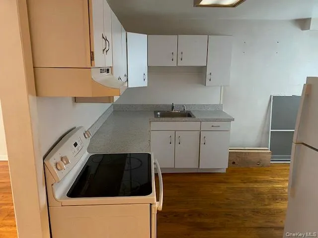 Kitchen featuring white appliances, white cabinets, light countertops, and dark wood-type flooring Kitchen featuring white appliances, white cabinets, light countertops, and dark wood-type flooring