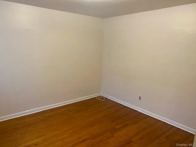 Unfurnished room featuring dark wood-style flooring and baseboards Unfurnished room featuring dark wood-style flooring and baseboards