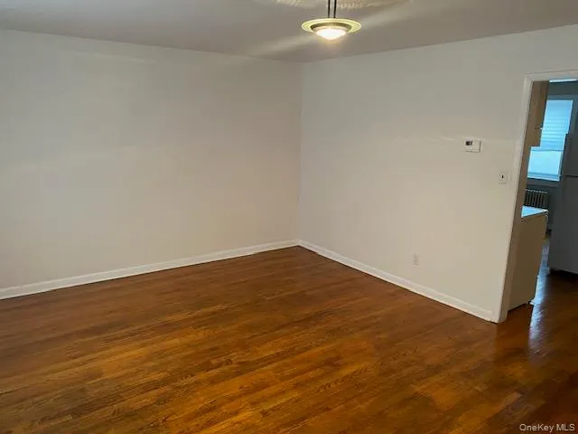 Spare room featuring dark wood-style flooring and baseboards Spare room featuring dark wood-style flooring and baseboards