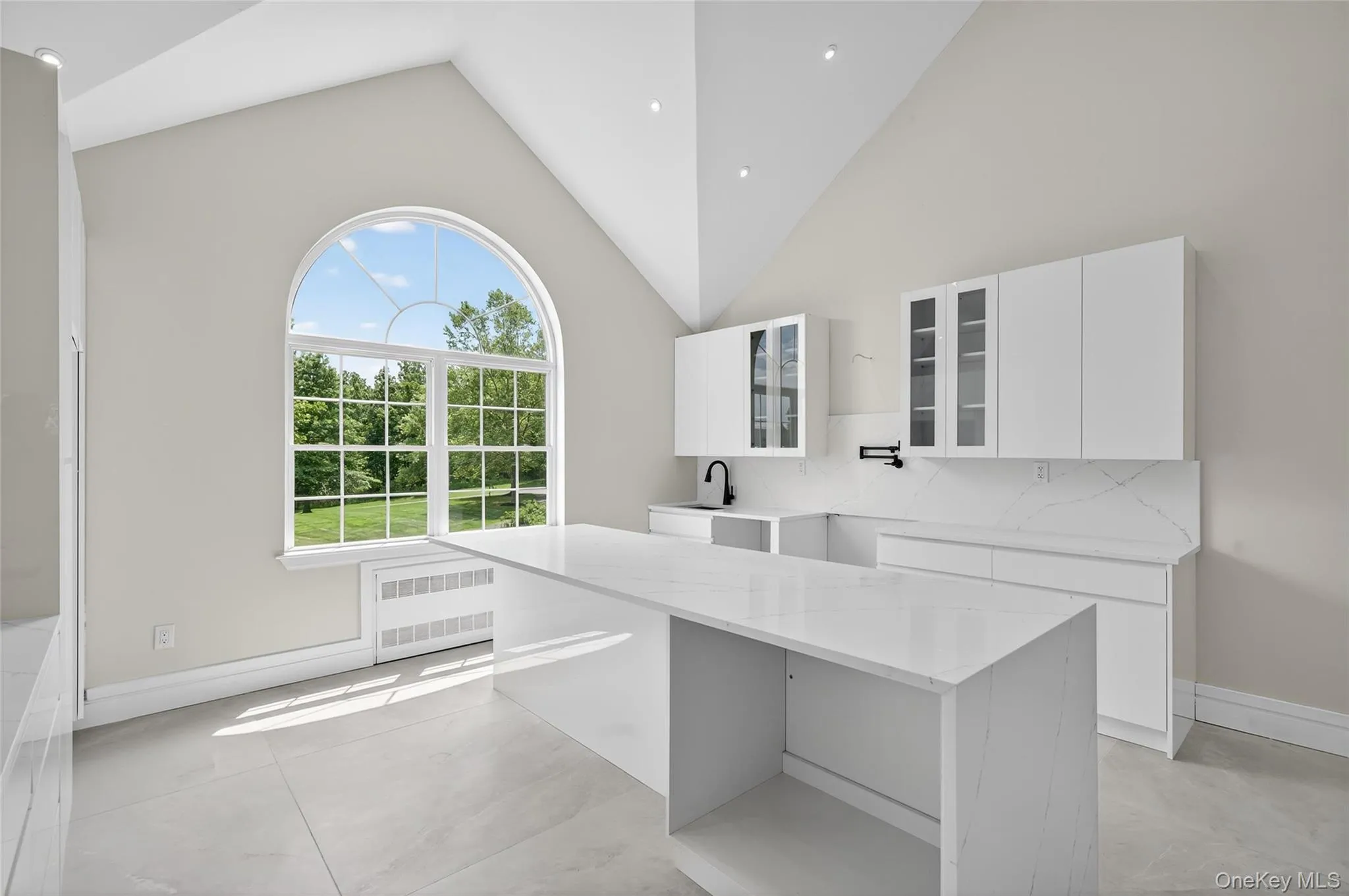 Kitchen with light stone counters, glass insert cabinets, white cabinets, high vaulted ceiling, and decorative backsplash Kitchen with light stone counters, glass insert cabinets, white cabinets, high vaulted ceiling, and decorative backsplash