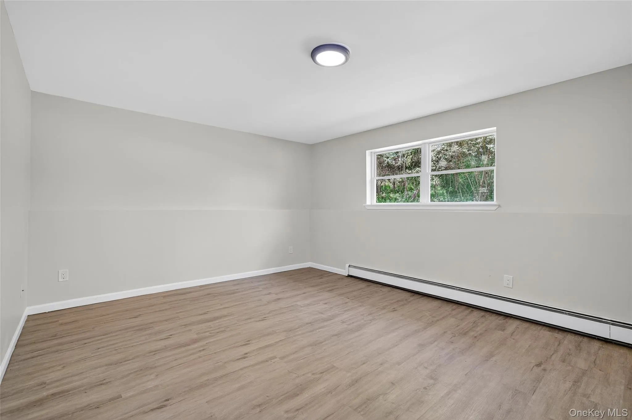 Spare room featuring baseboard heating and light wood finished floors Spare room featuring baseboard heating and light wood finished floors