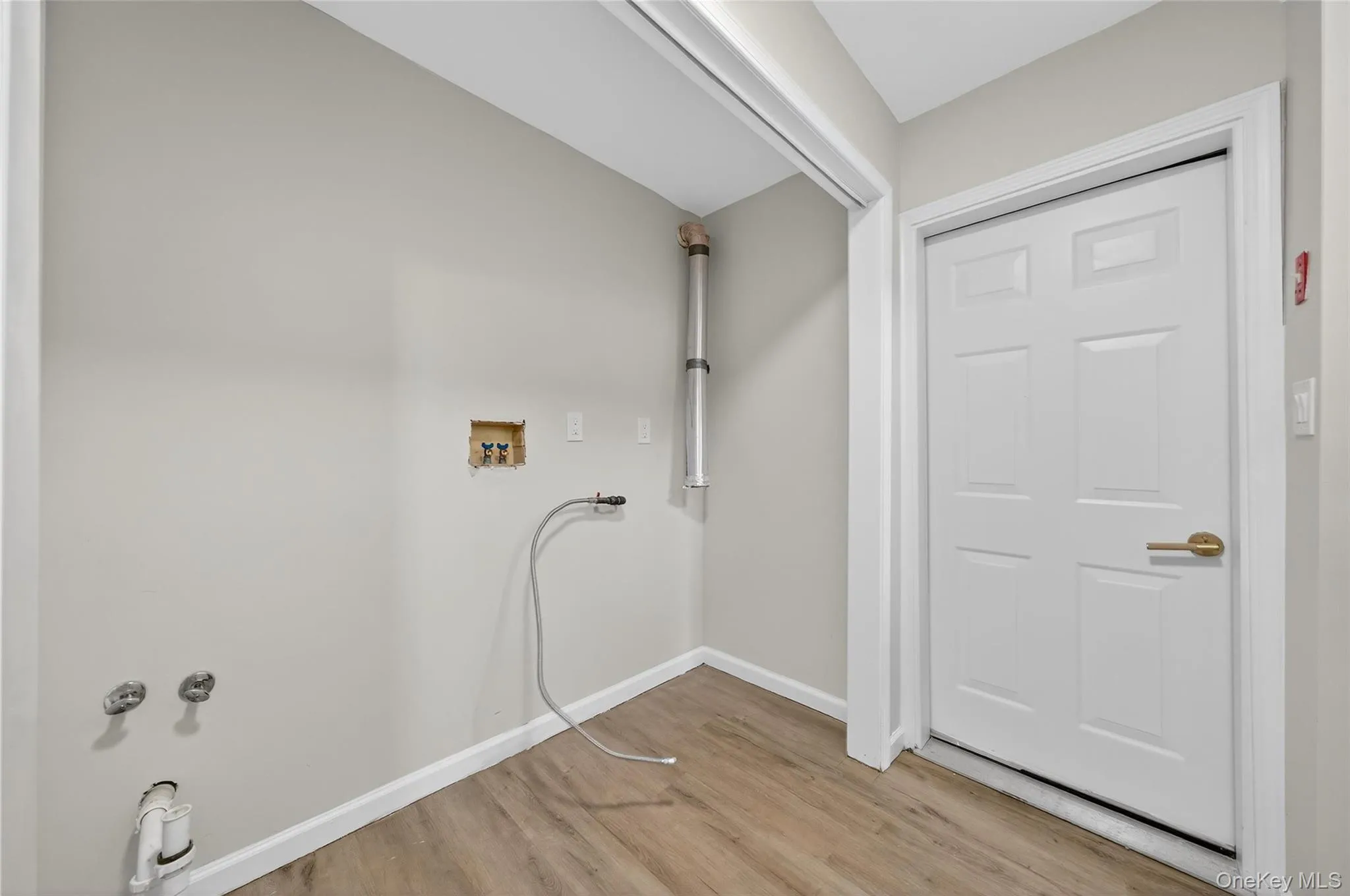 Washroom featuring washer hookup and light wood-style floors Washroom featuring washer hookup and light wood-style floors