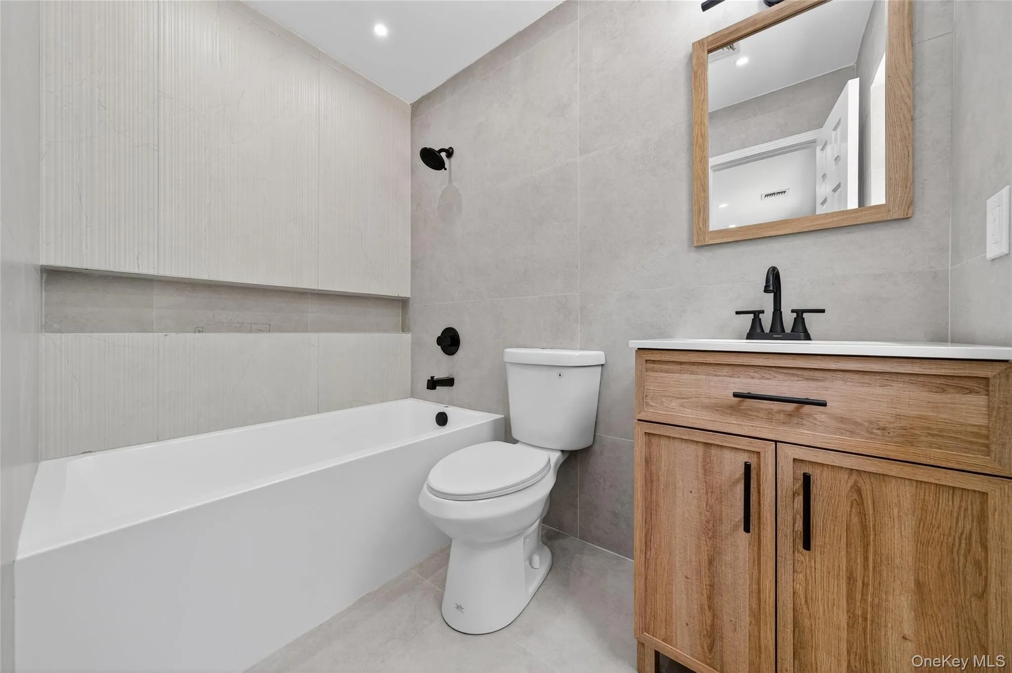 Bathroom featuring tile walls, vanity, shower / tub combination, and light tile patterned floors Bathroom featuring tile walls, vanity, shower / tub combination, and light tile patterned floors