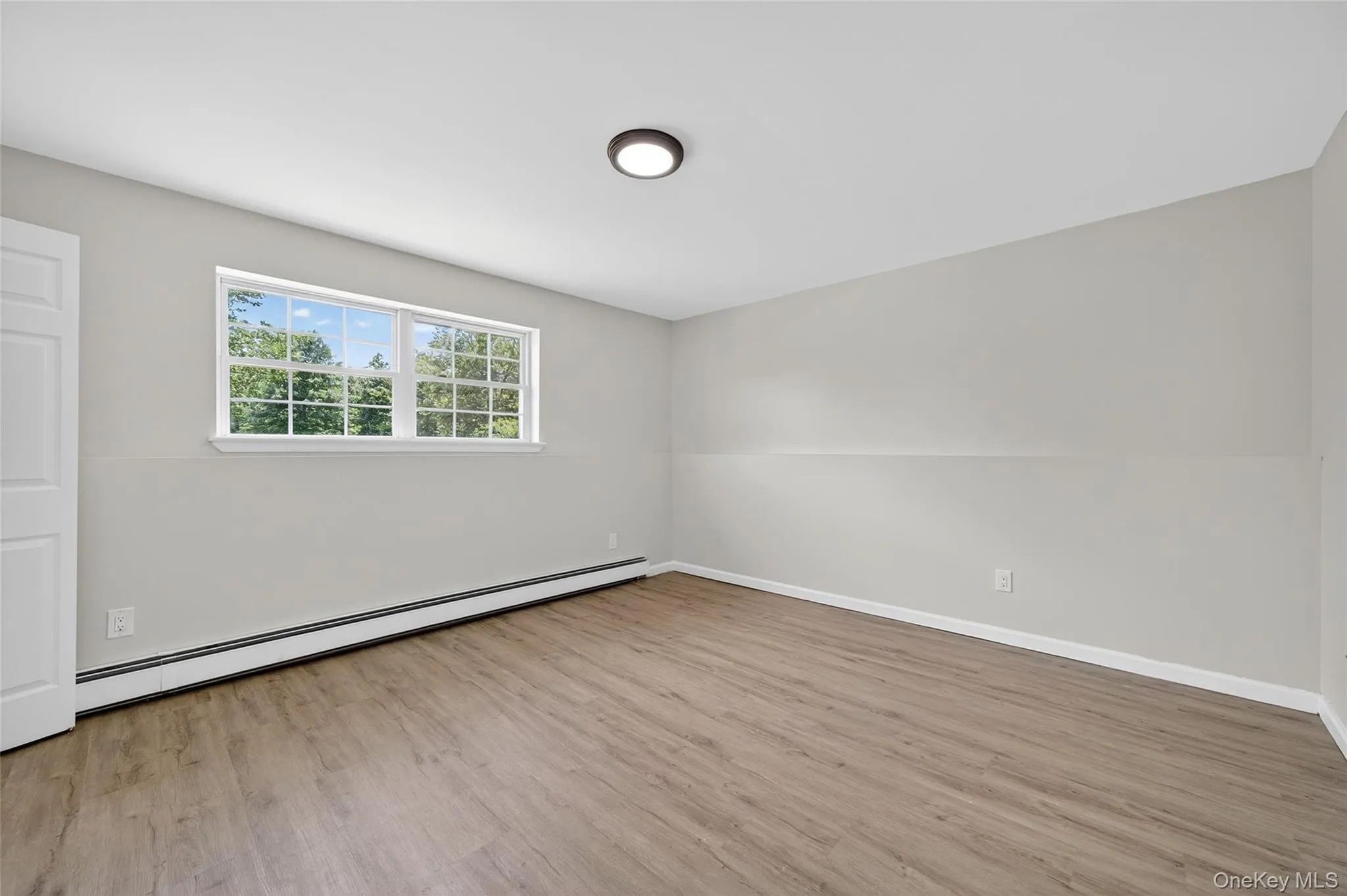 Unfurnished room with a baseboard radiator and light wood-type flooring Unfurnished room with a baseboard radiator and light wood-type flooring