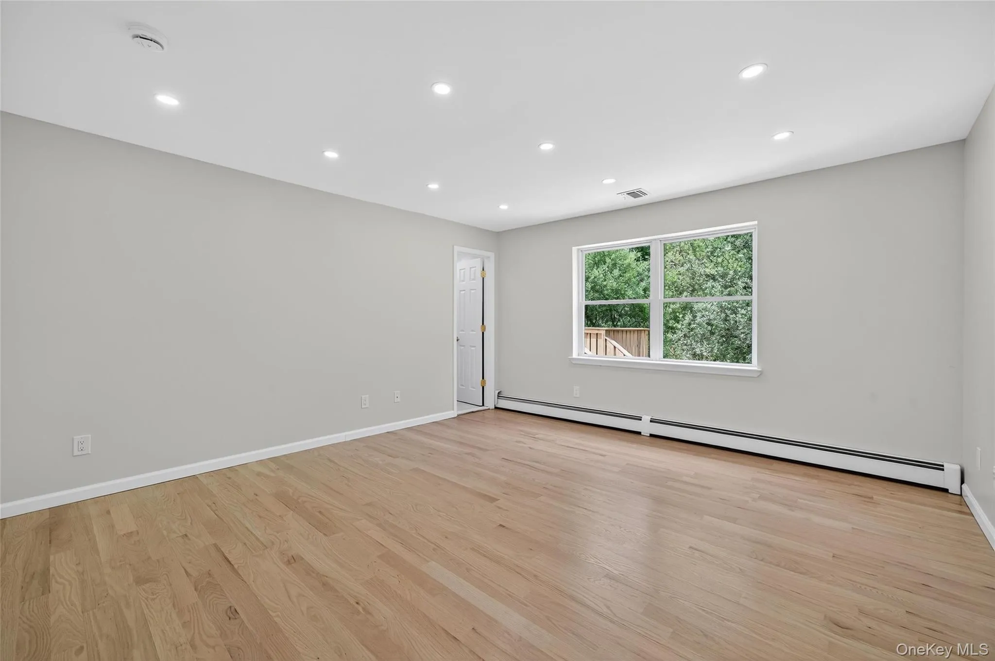 Unfurnished room with recessed lighting, a baseboard heating unit, and light wood-style floors Unfurnished room with recessed lighting, a baseboard heating unit, and light wood-style floors