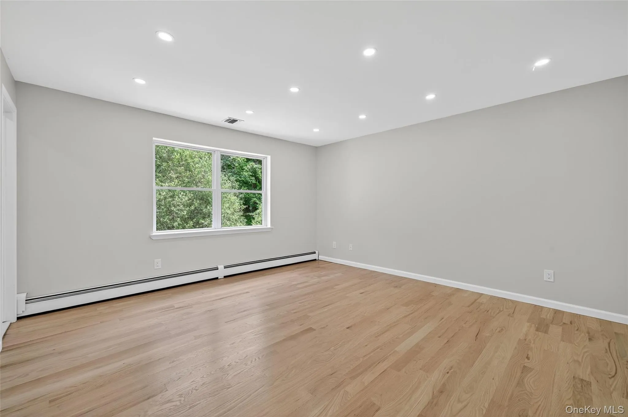 Unfurnished room with recessed lighting, a baseboard heating unit, and light wood-style flooring Unfurnished room with recessed lighting, a baseboard heating unit, and light wood-style flooring