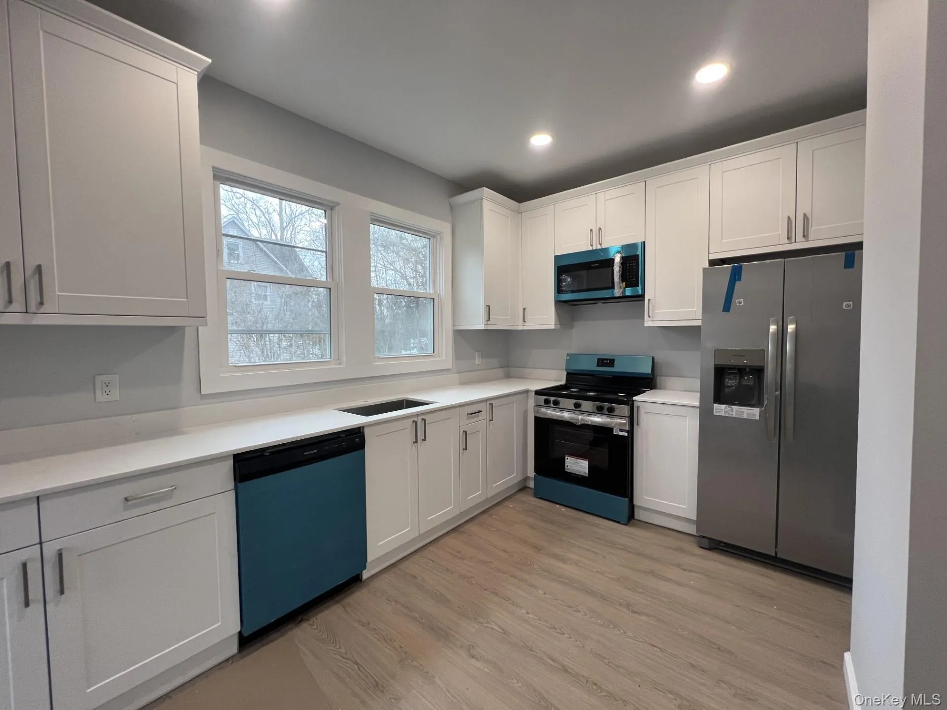 Kitchen with appliances with stainless steel finishes, white cabinetry, light wood finished floors, and recessed lighting Kitchen with appliances with stainless steel finishes, white cabinetry, light wood finished floors, and recessed lighting
