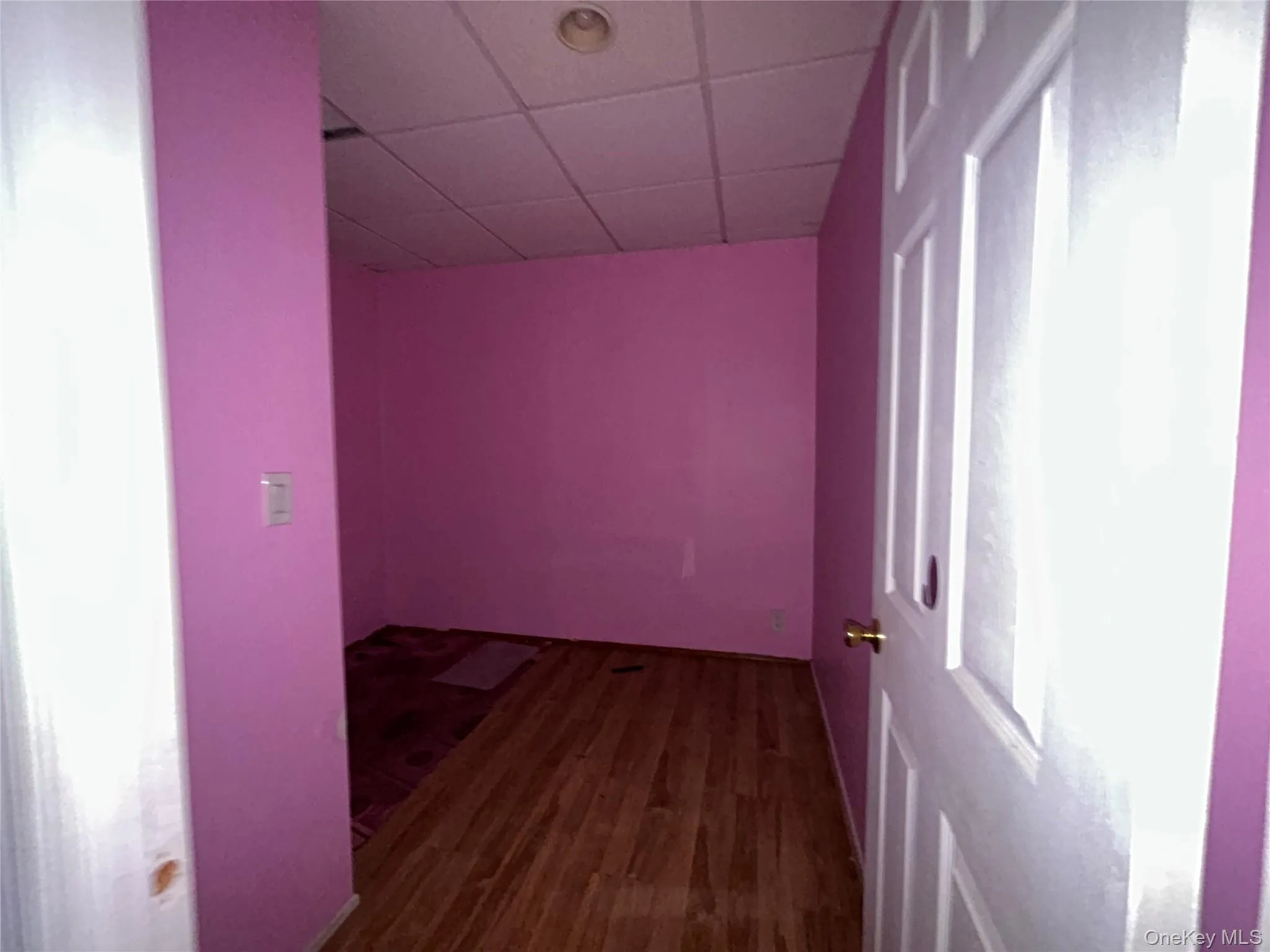 Hallway featuring a drop ceiling and dark wood-style flooring Hallway featuring a drop ceiling and dark wood-style flooring