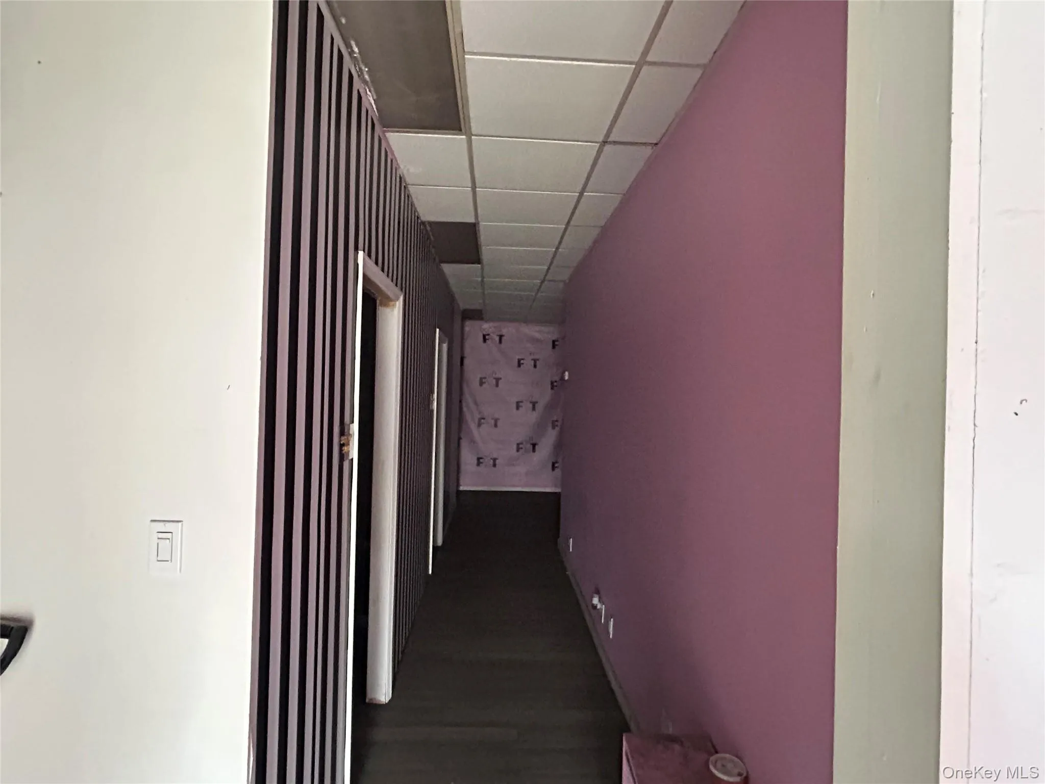 Hallway featuring a paneled ceiling and dark wood-type flooring Hallway featuring a paneled ceiling and dark wood-type flooring
