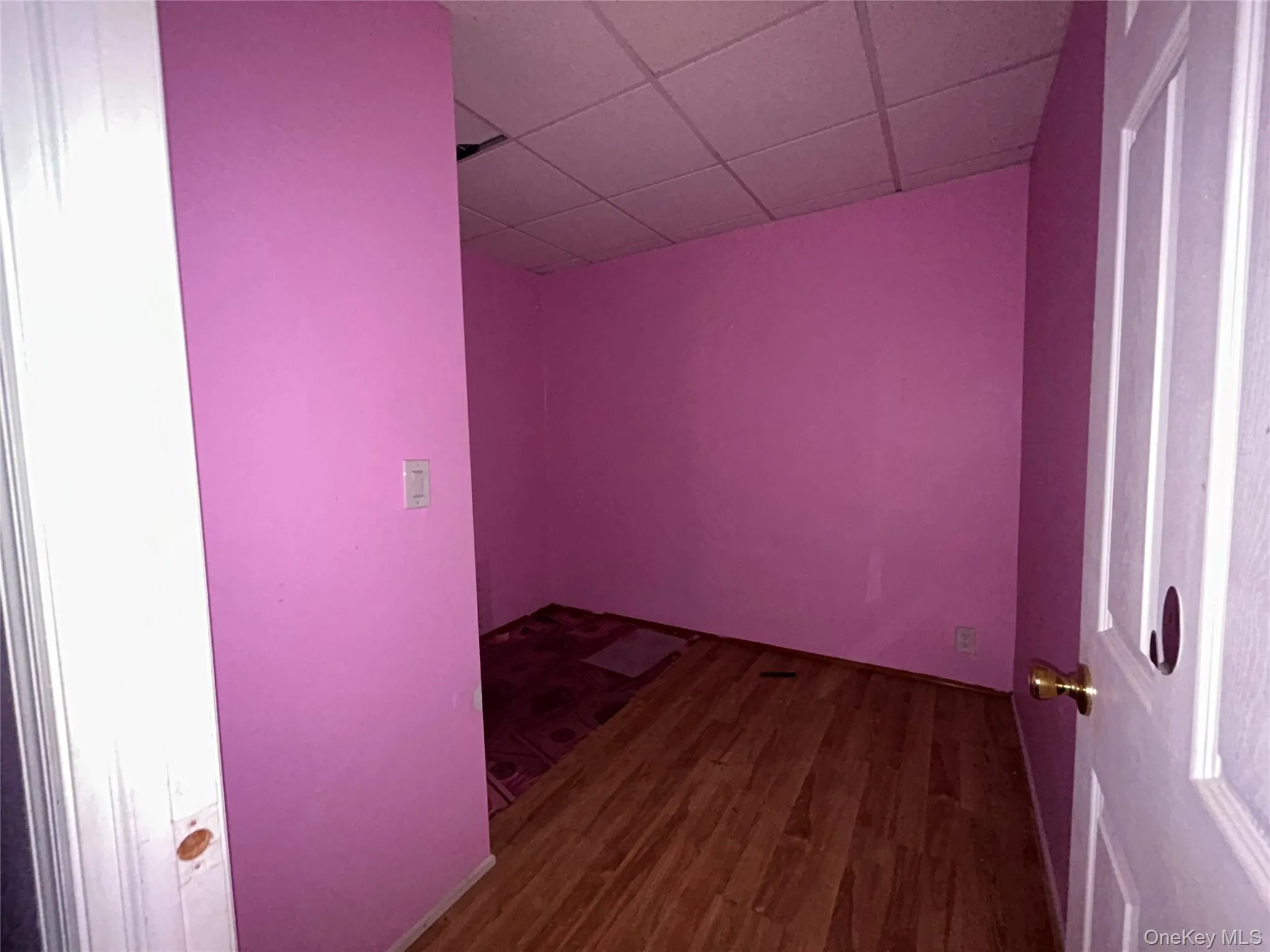Empty room featuring a drop ceiling and dark wood-style floors Empty room featuring a drop ceiling and dark wood-style floors